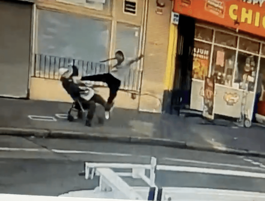On a San Francisco sidewalk, a suspect leaps in the air to kick a man in a seater walker.
