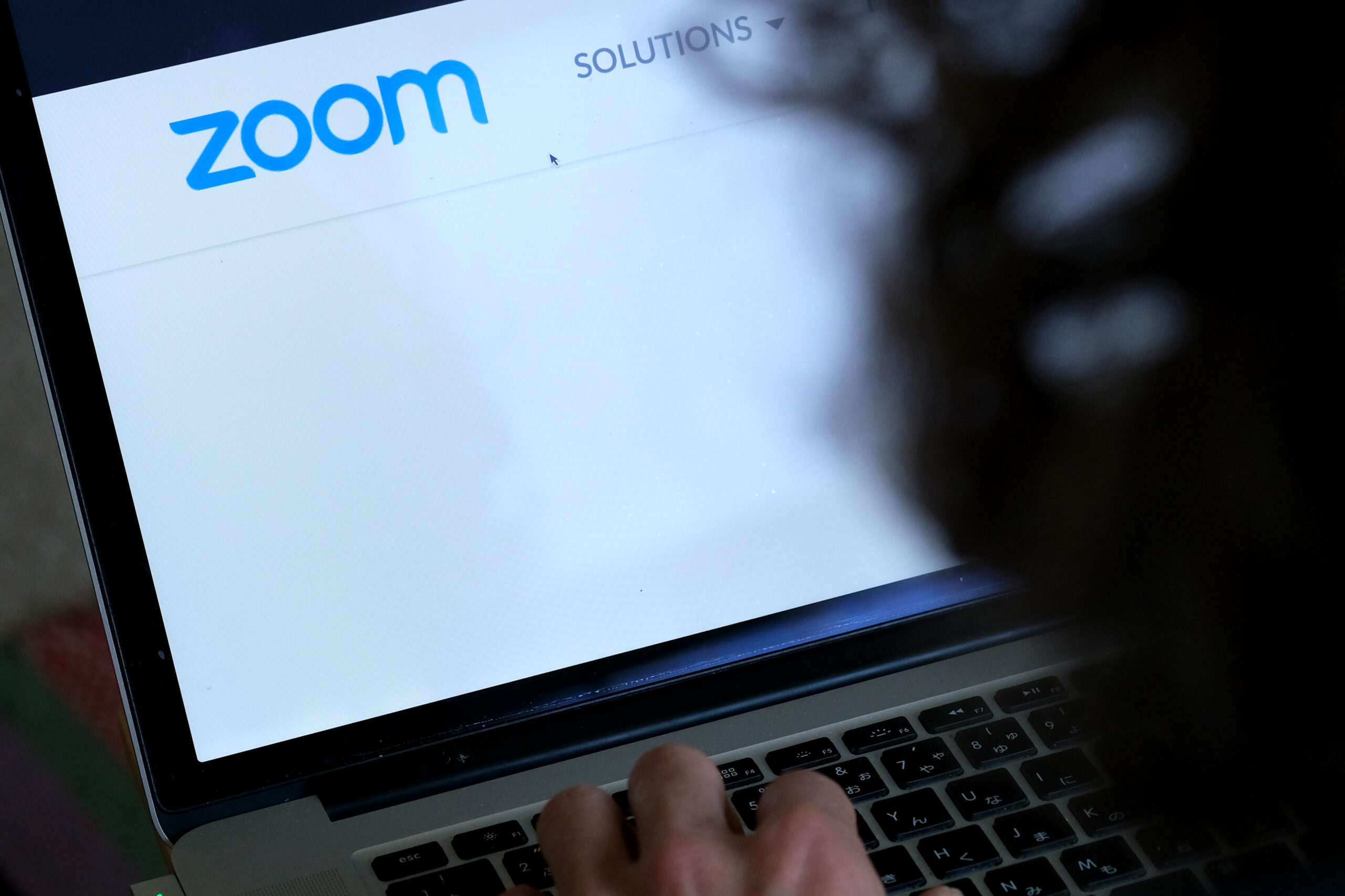 A laptop shows a webpage for Zoom