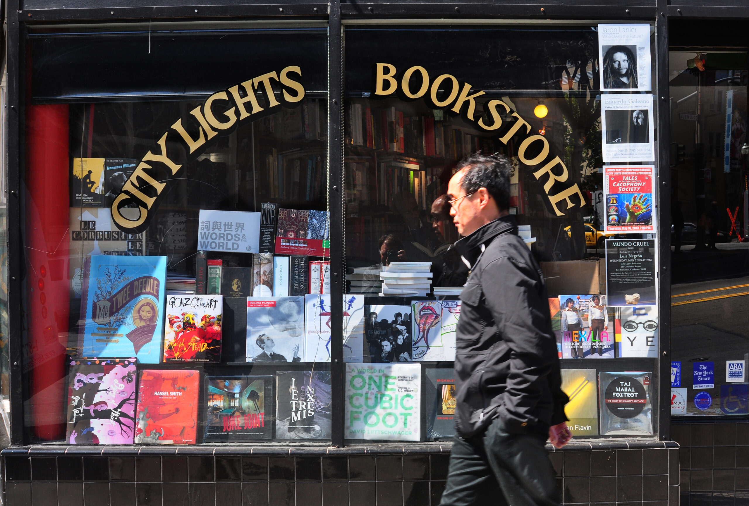 A storefront of City Lights Books with a man walking by.