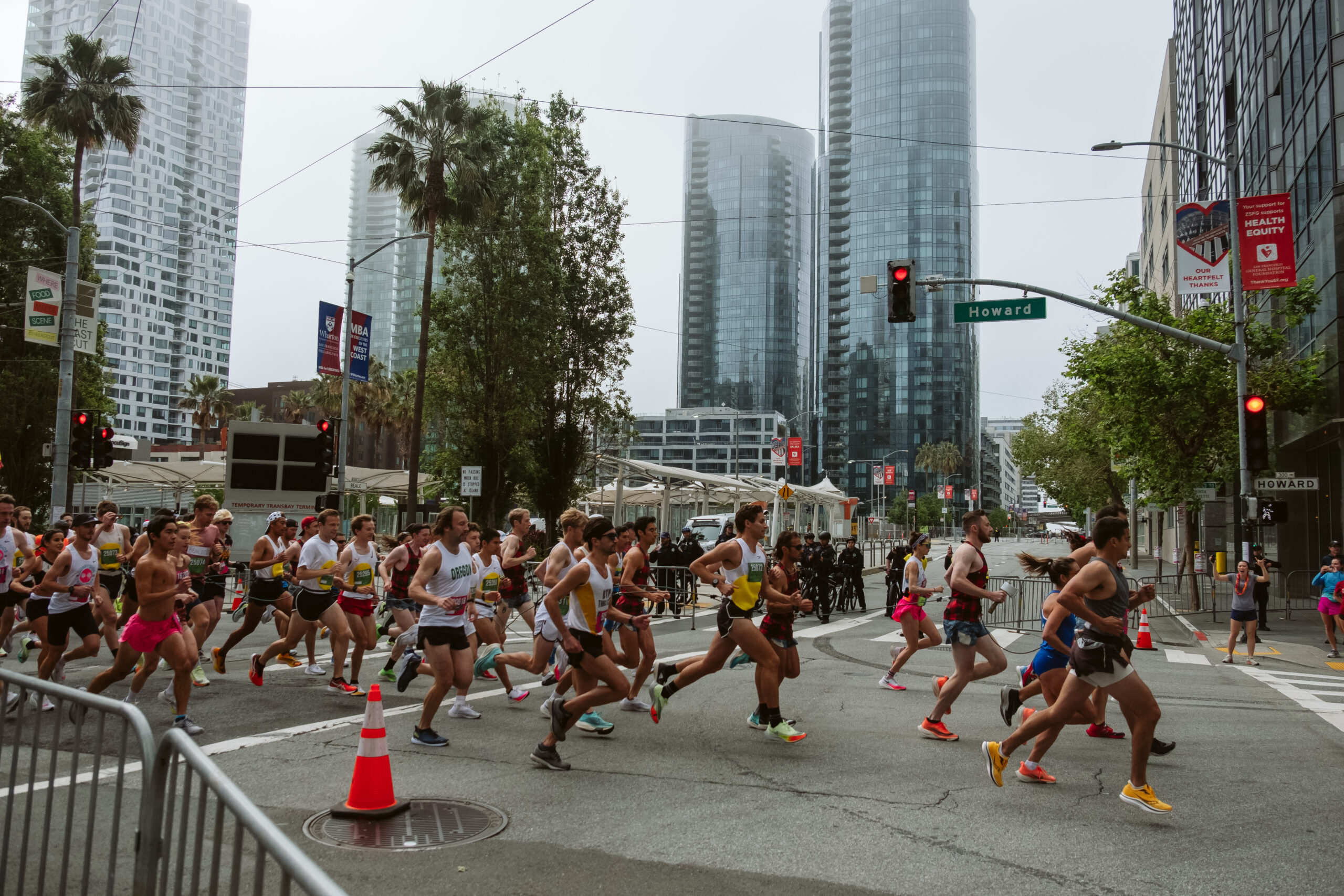 People run through a closed intersection with high-rise buildings in the background