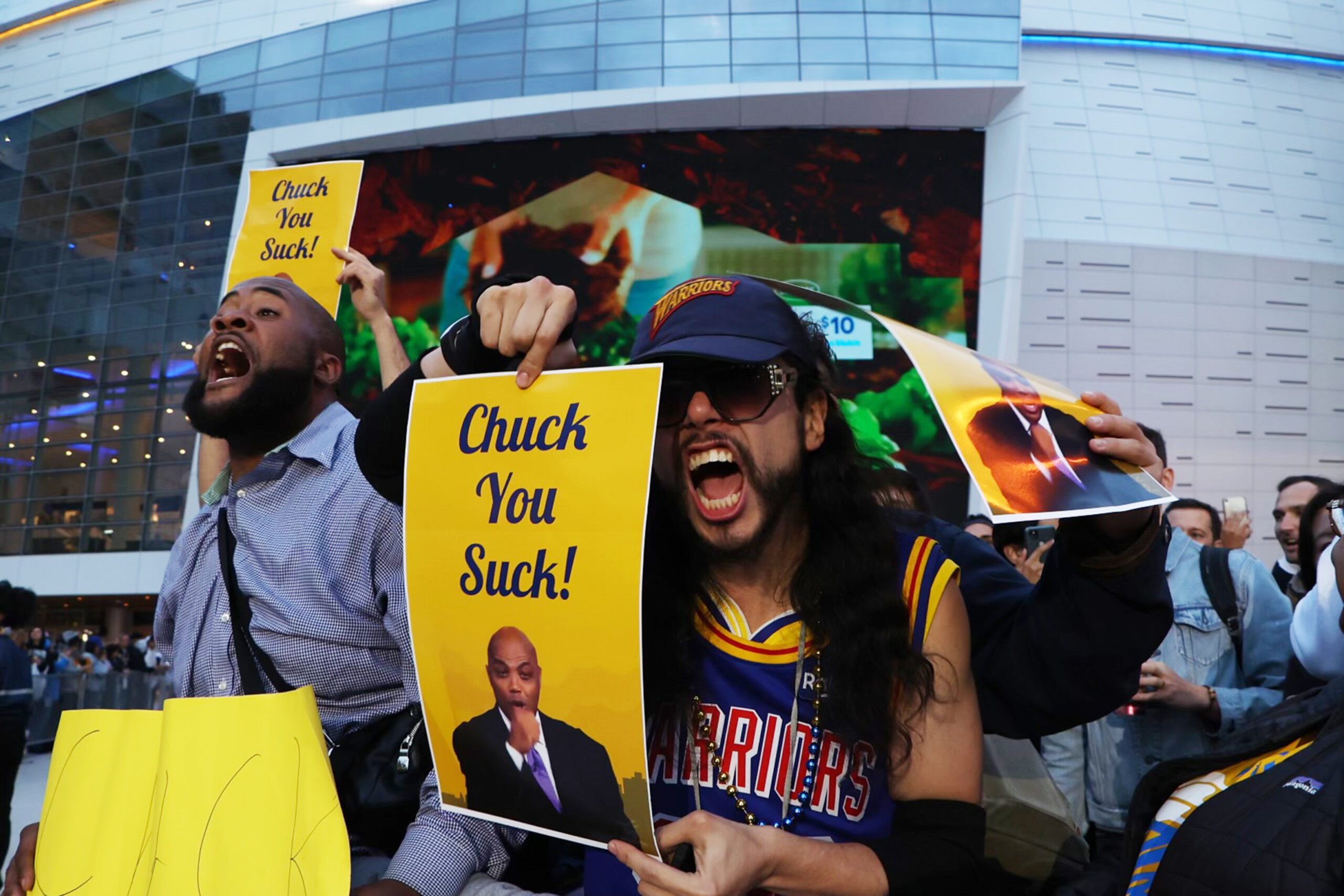 guy in jersey holding a poster that reads chuck you suck