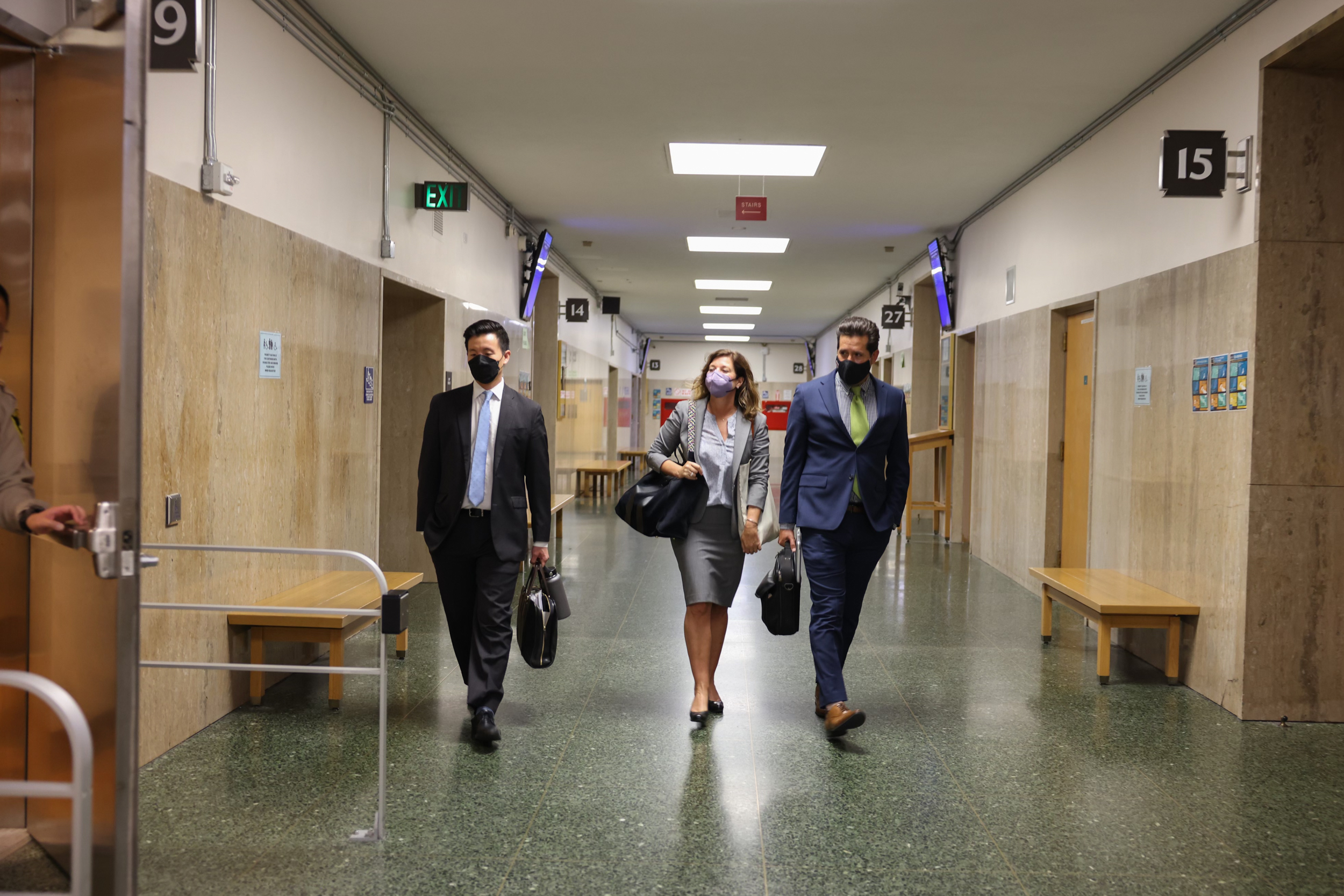 Three people walk through a hallway.
