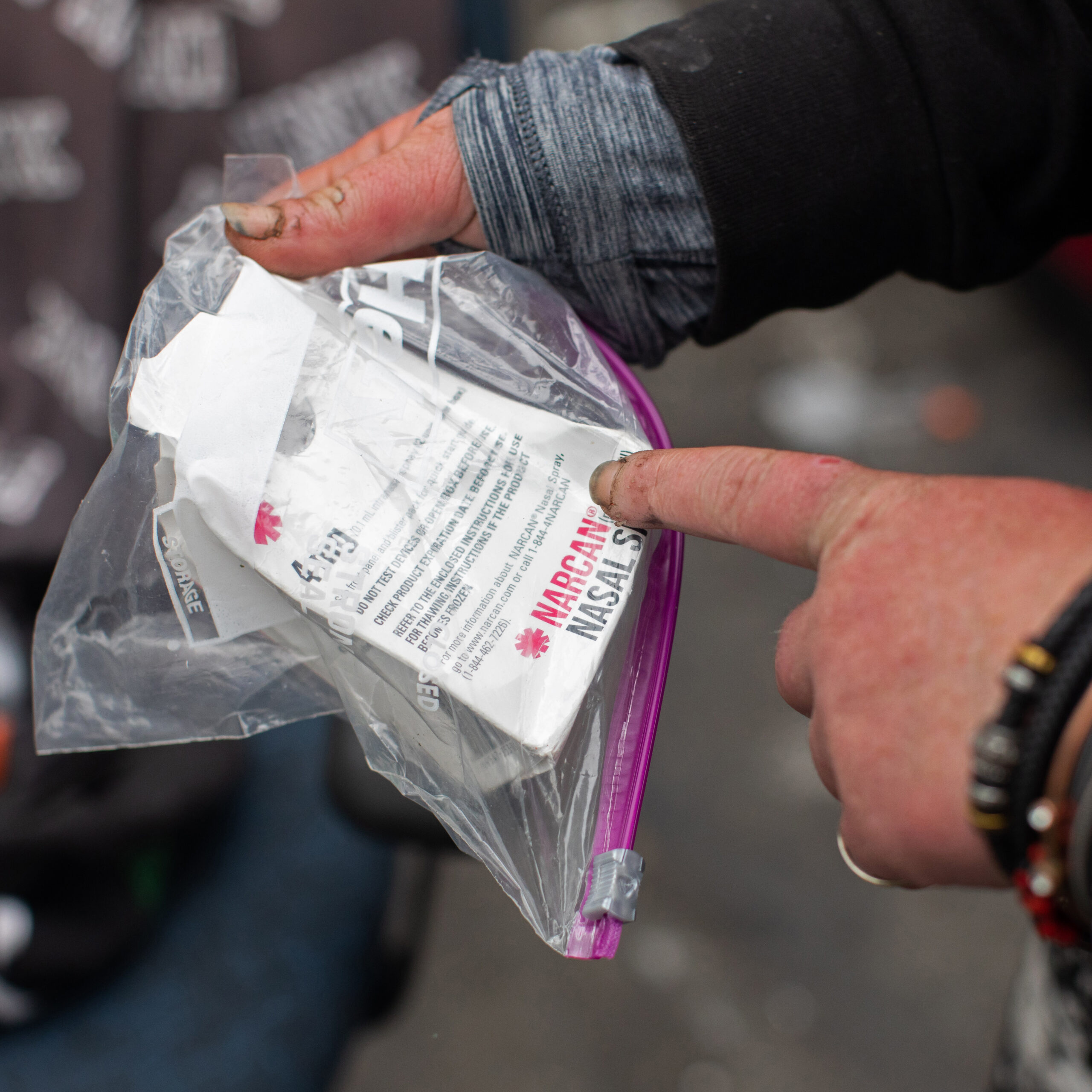 A woman points to a box of narcan.