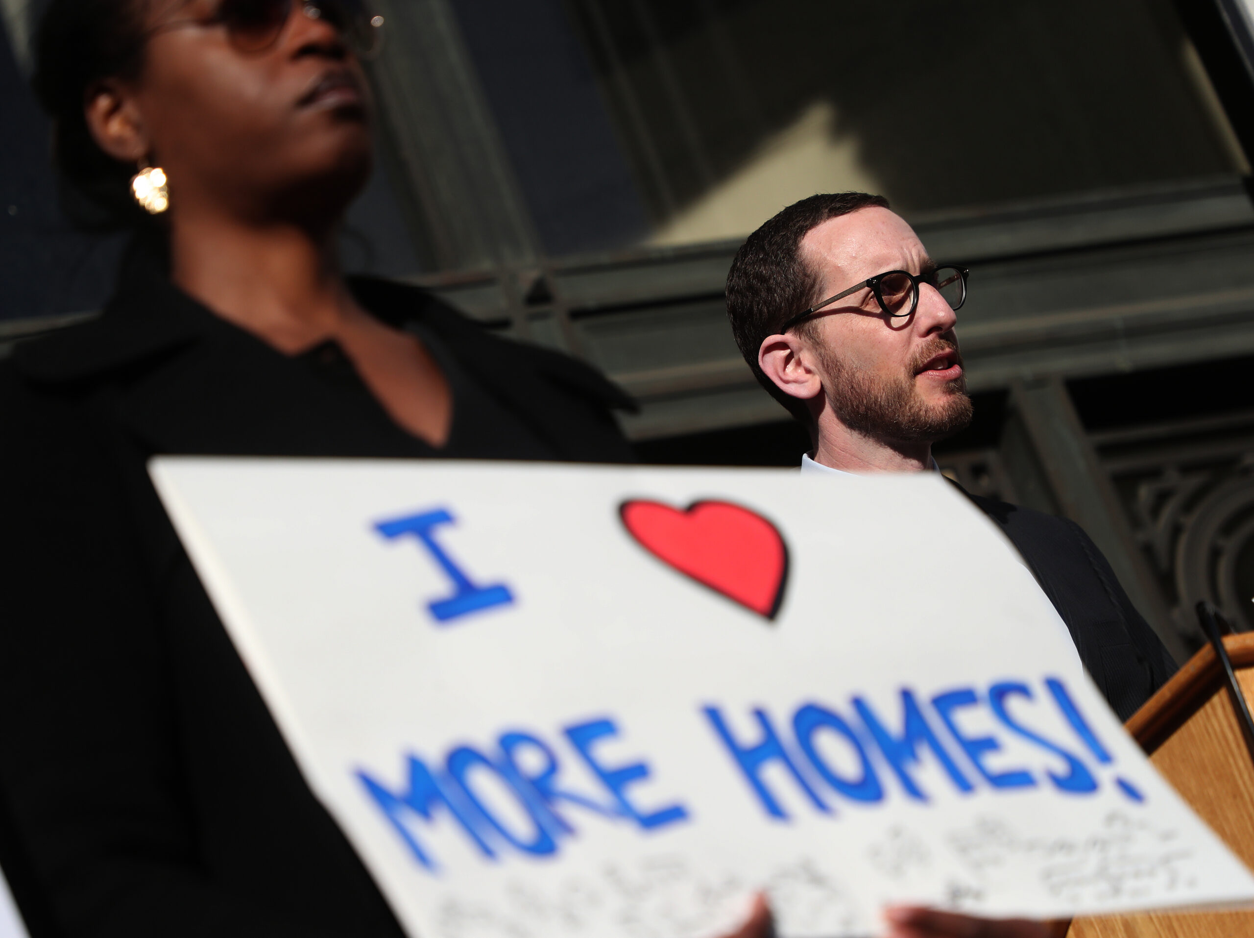 A headshot of Scott Wiener and a protest sign held by someone else reading I LOVE MORE HOMES!