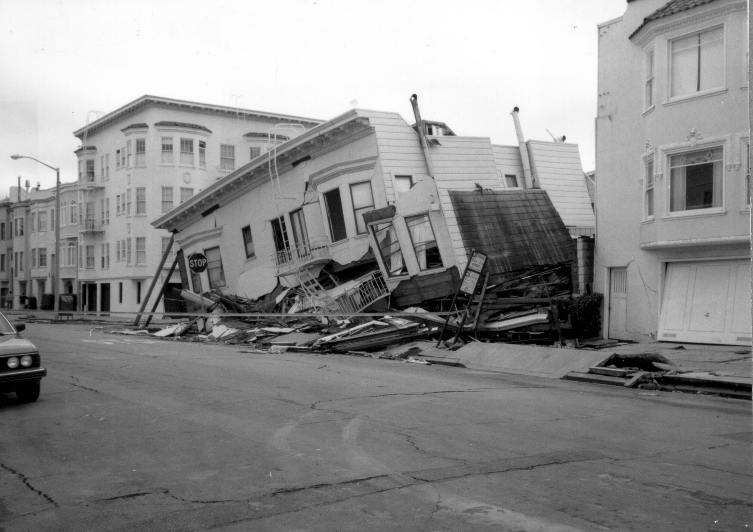 A black-and-white photo of a collapsed two-story building.
