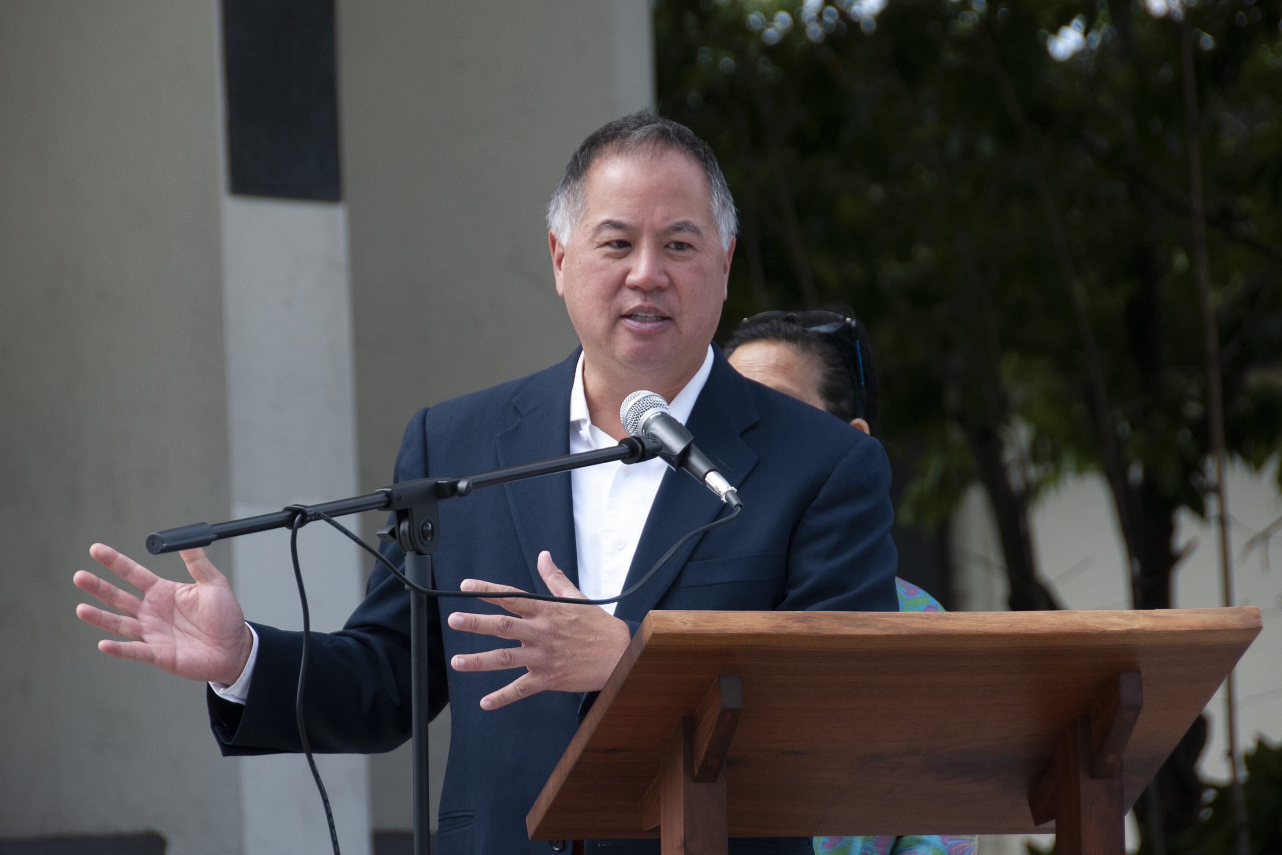 man in a blue suit speaks at a podium