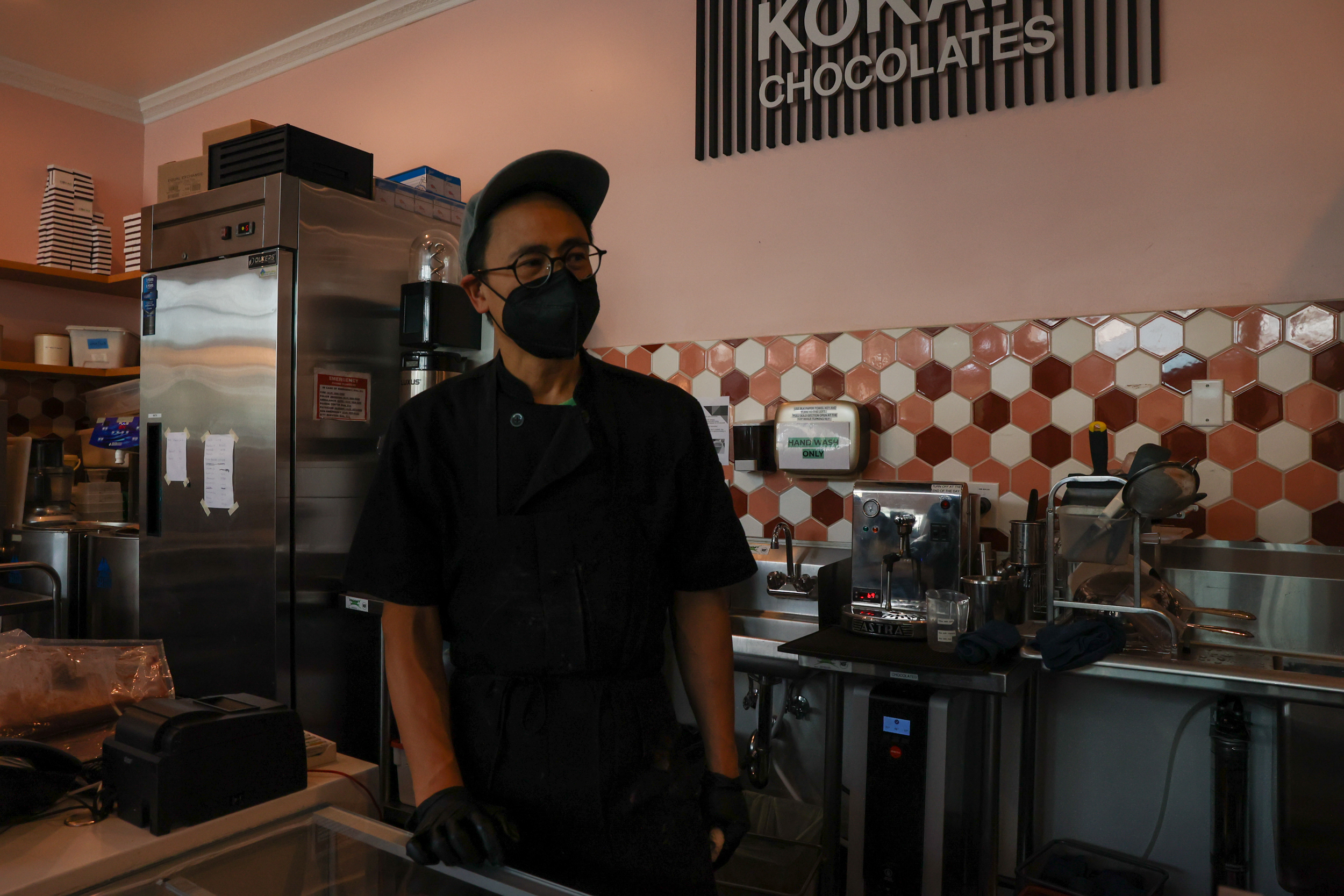 A man in a mask stands in a kitchen.