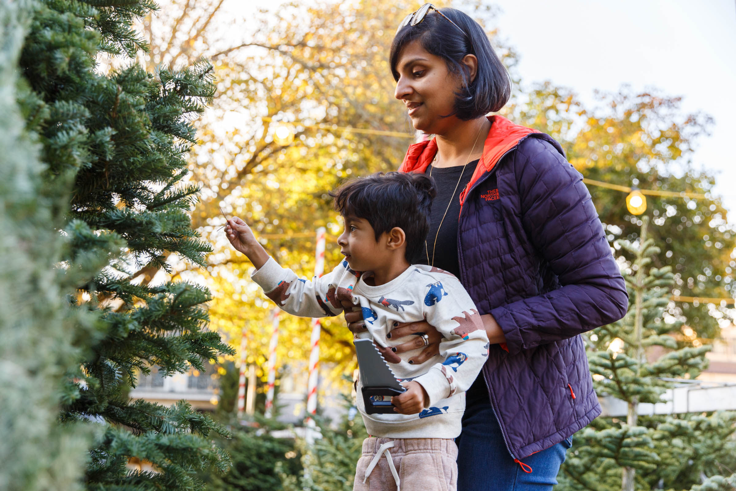 A woman and her son look at a Christmas tree together.