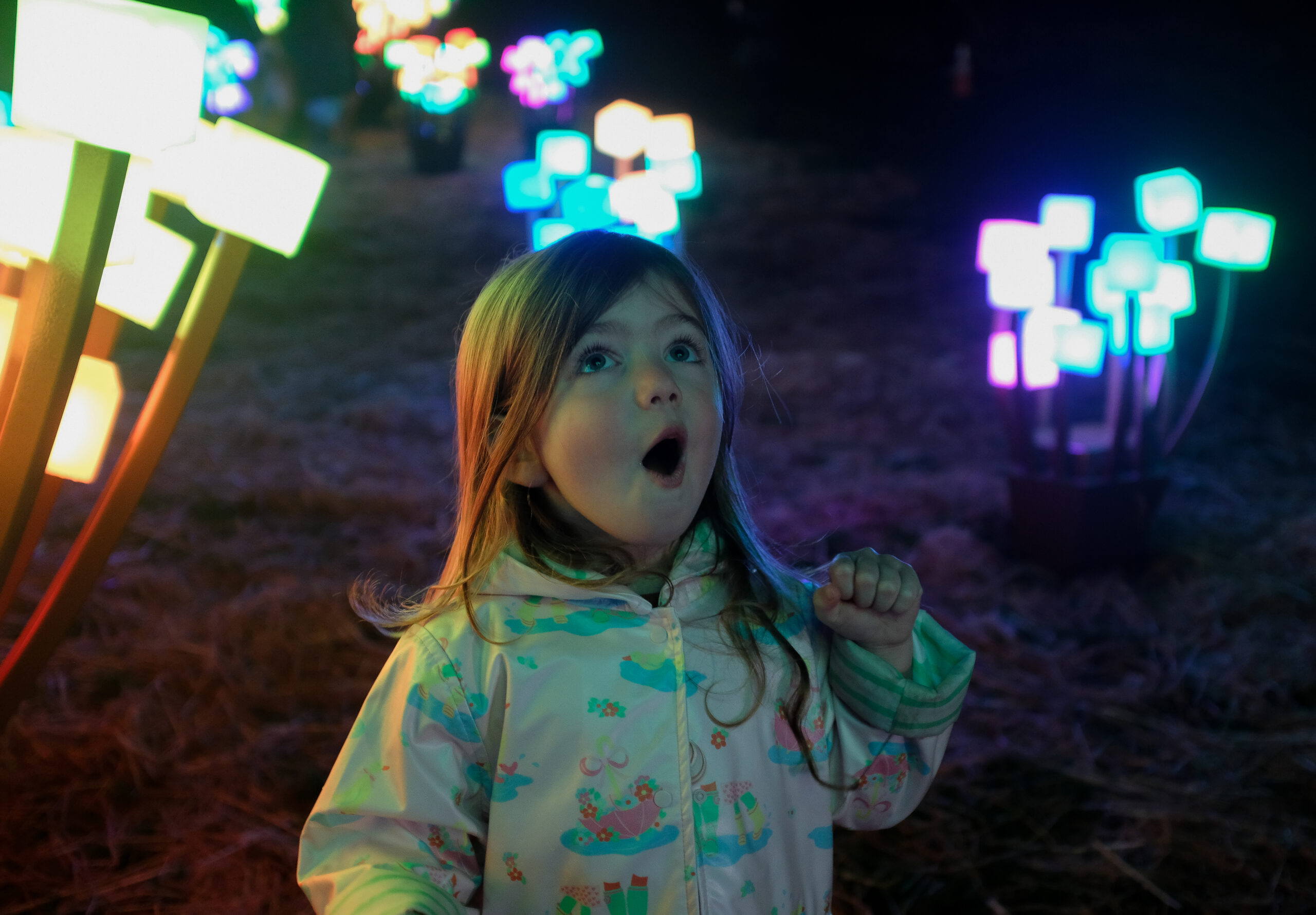 A little girl looks at holiday lights in awe.