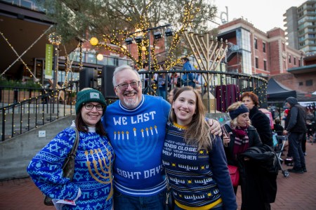 A family stands in Ghiradelli square wearing matching Hanukkah sweaters.