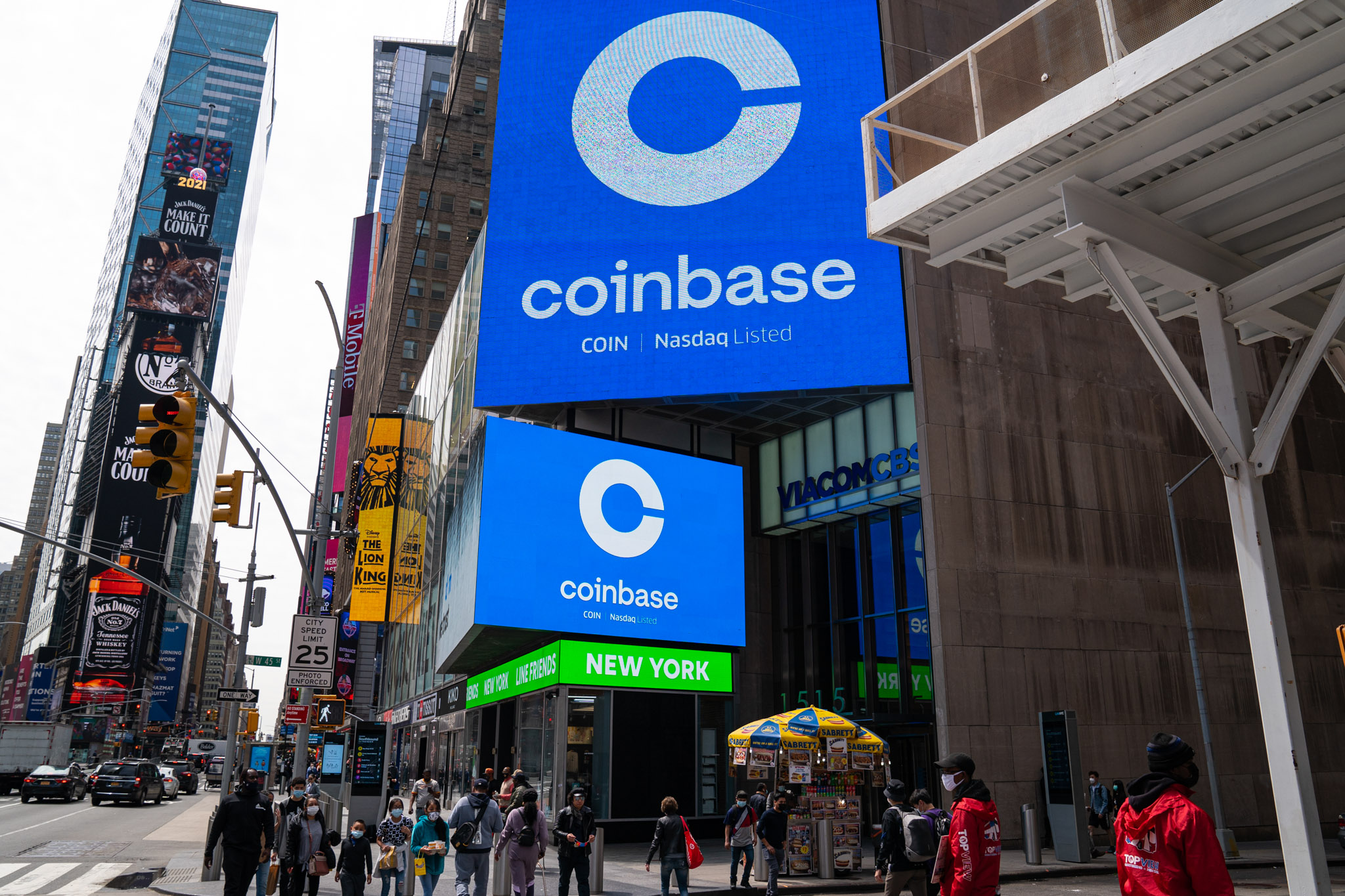 Coinbase's logo is displayed on two screens in New York City