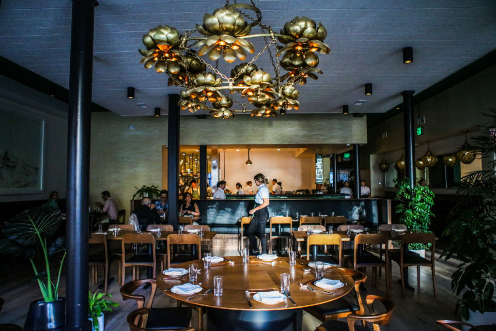 Wooden tables and chandelier light fixtures are pictured in a restaurant in San Francisco's Chinatown.