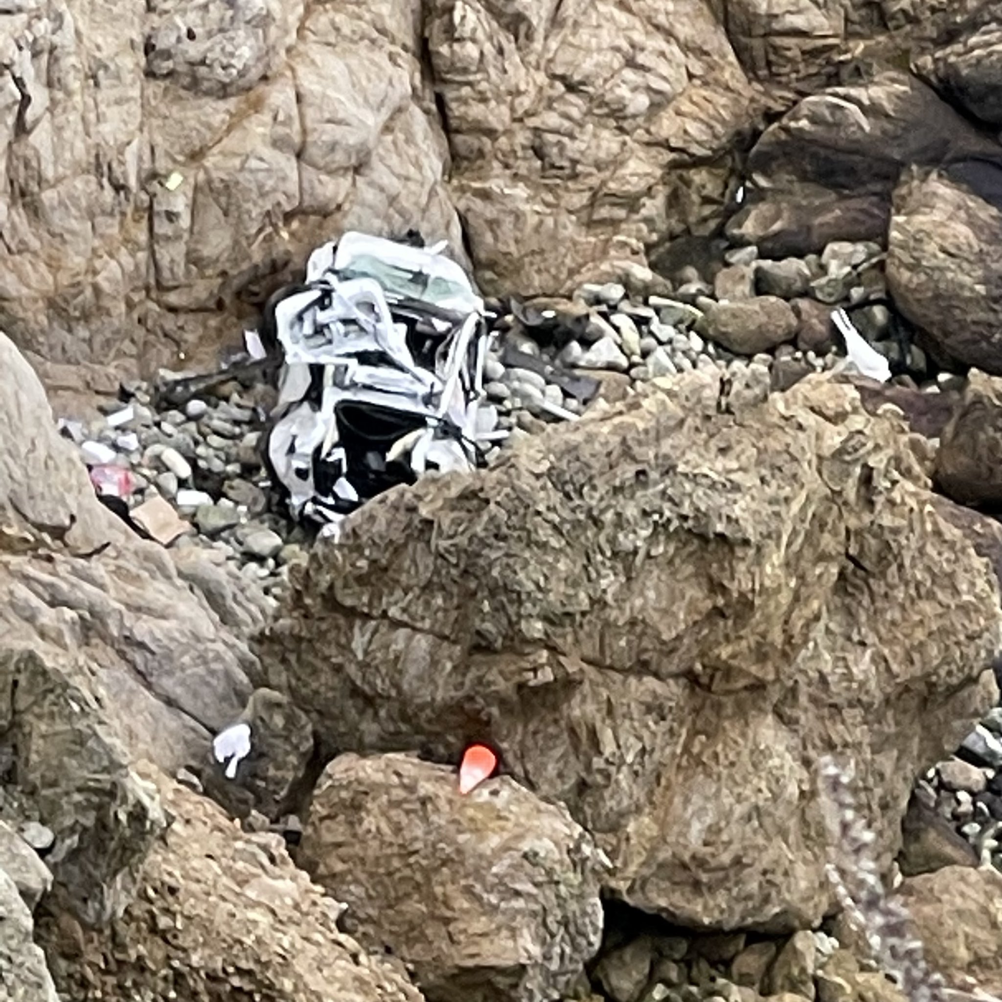 White Tesla smashed on rocks off of Highway 1.