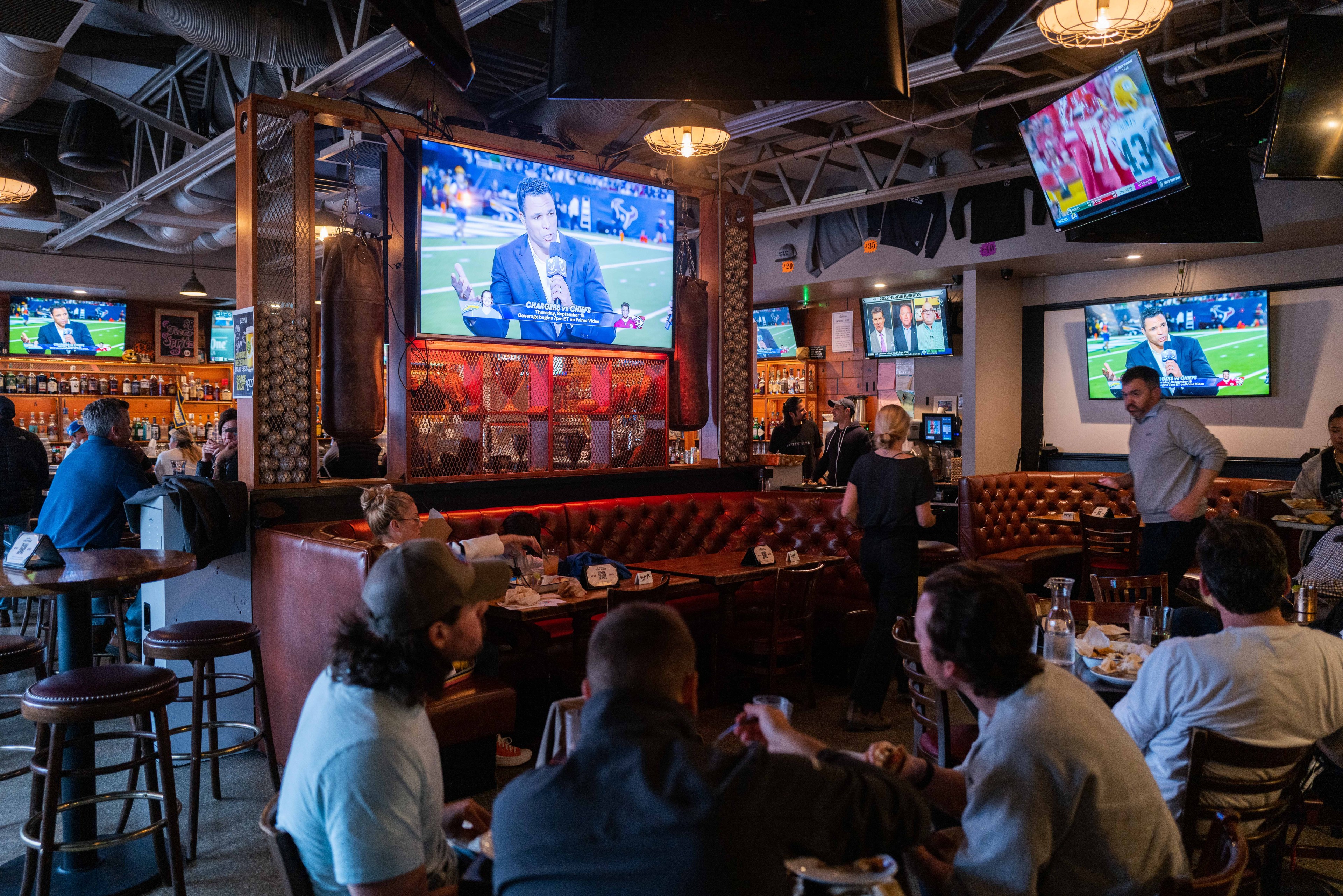 A sports bar has people crowded around watching a television. 