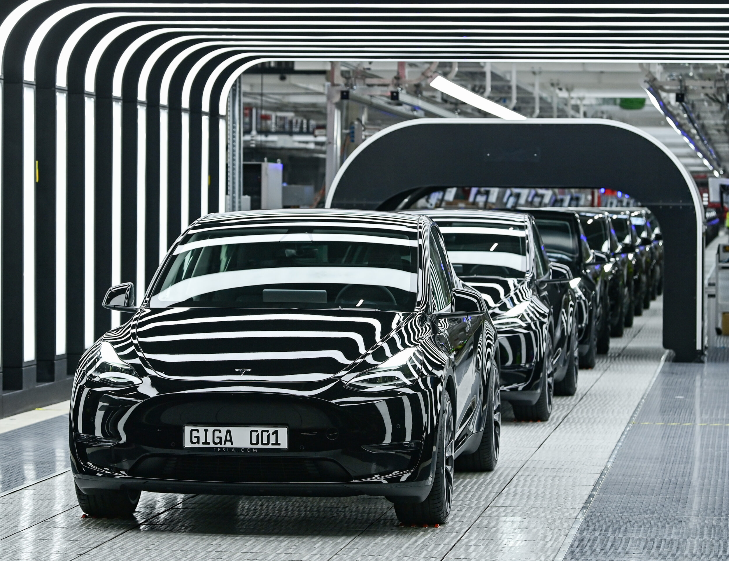 Several Model Y electric vehicles stand on a conveyor belt at the opening of the Tesla Gigafactory Berlin Brandenburg on March 22, 2022 in Brandenburg, Grünheide, Germany. The first European factory in Grünheide, which is designed for 500,000 vehicles per year, is an important pillar of Tesla's future strategy. | Patrick Pleul/picture alliance via Getty Images