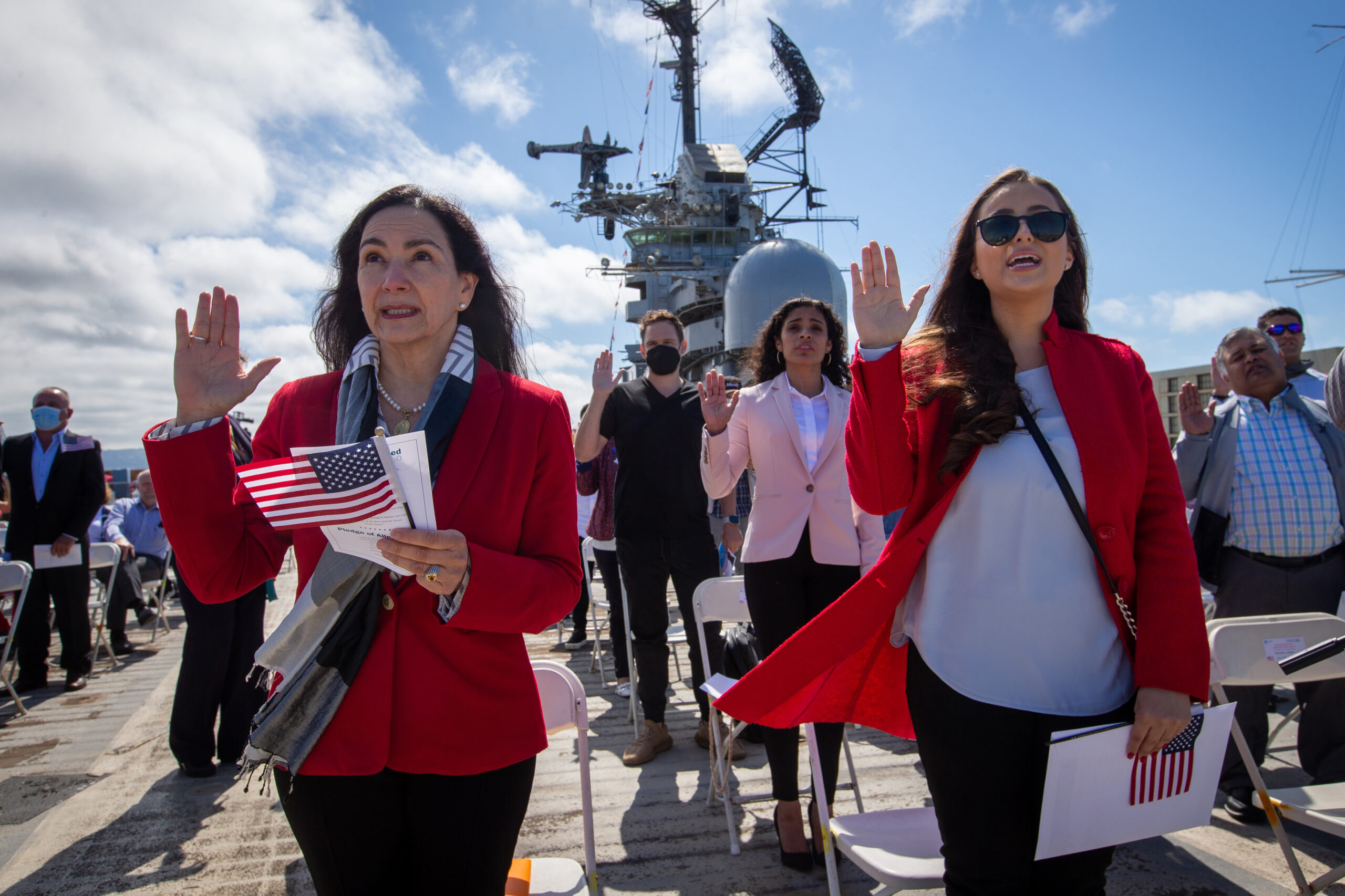 Maria Laura Limpias Chavez, left, of Bolivia, Sahara Loffsner, of Colombia, and fellow new American citizens, take the Oath of Allegiance during a naturalization ceremony on the flight deck of the USS Hornet Museum in Alameda in July 2021. | Ray Chavez/MediaNews Group/The Mercury News via Getty Images