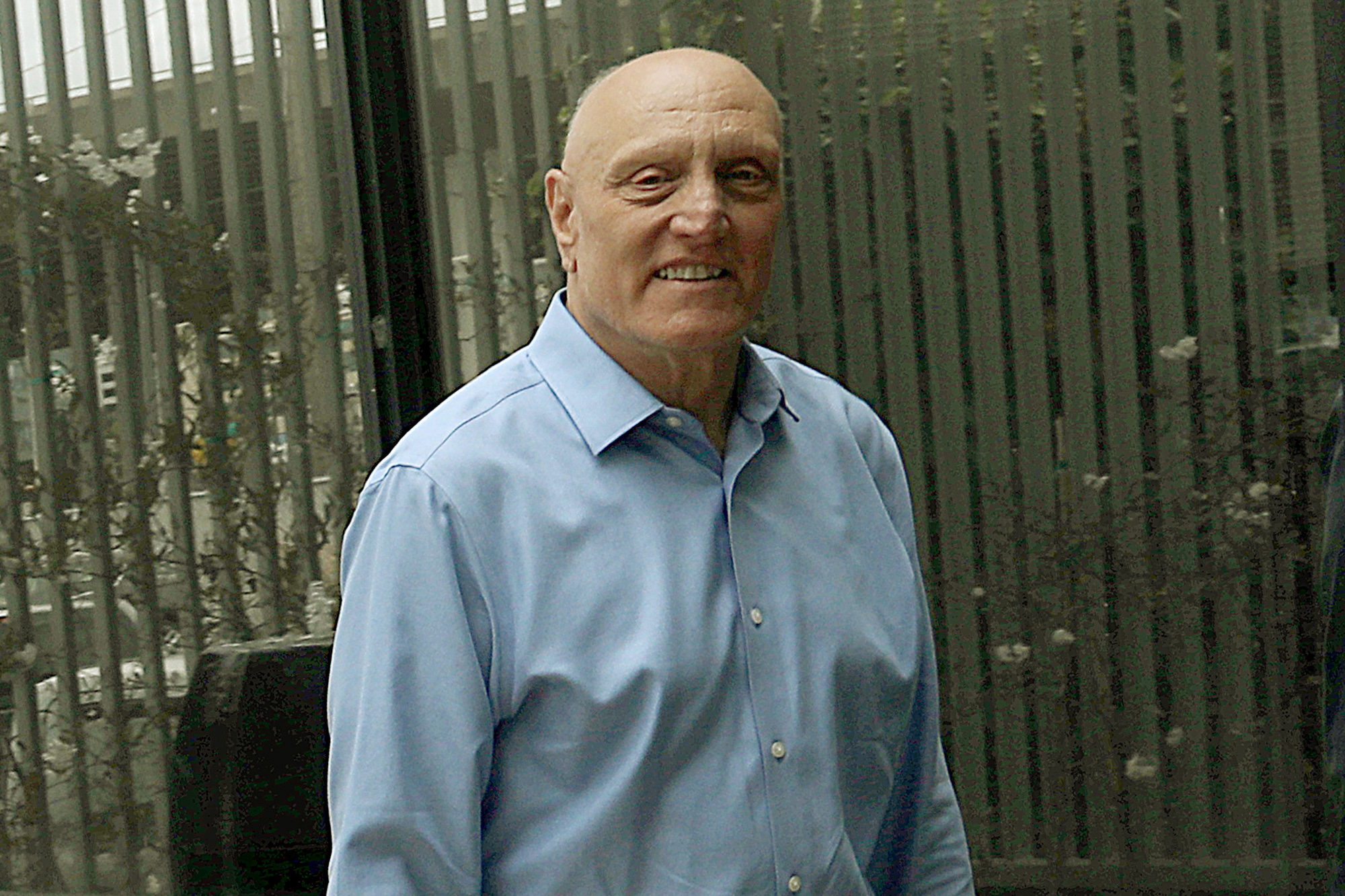 Paul Giusti poses for a photo wearing a blue button-down.