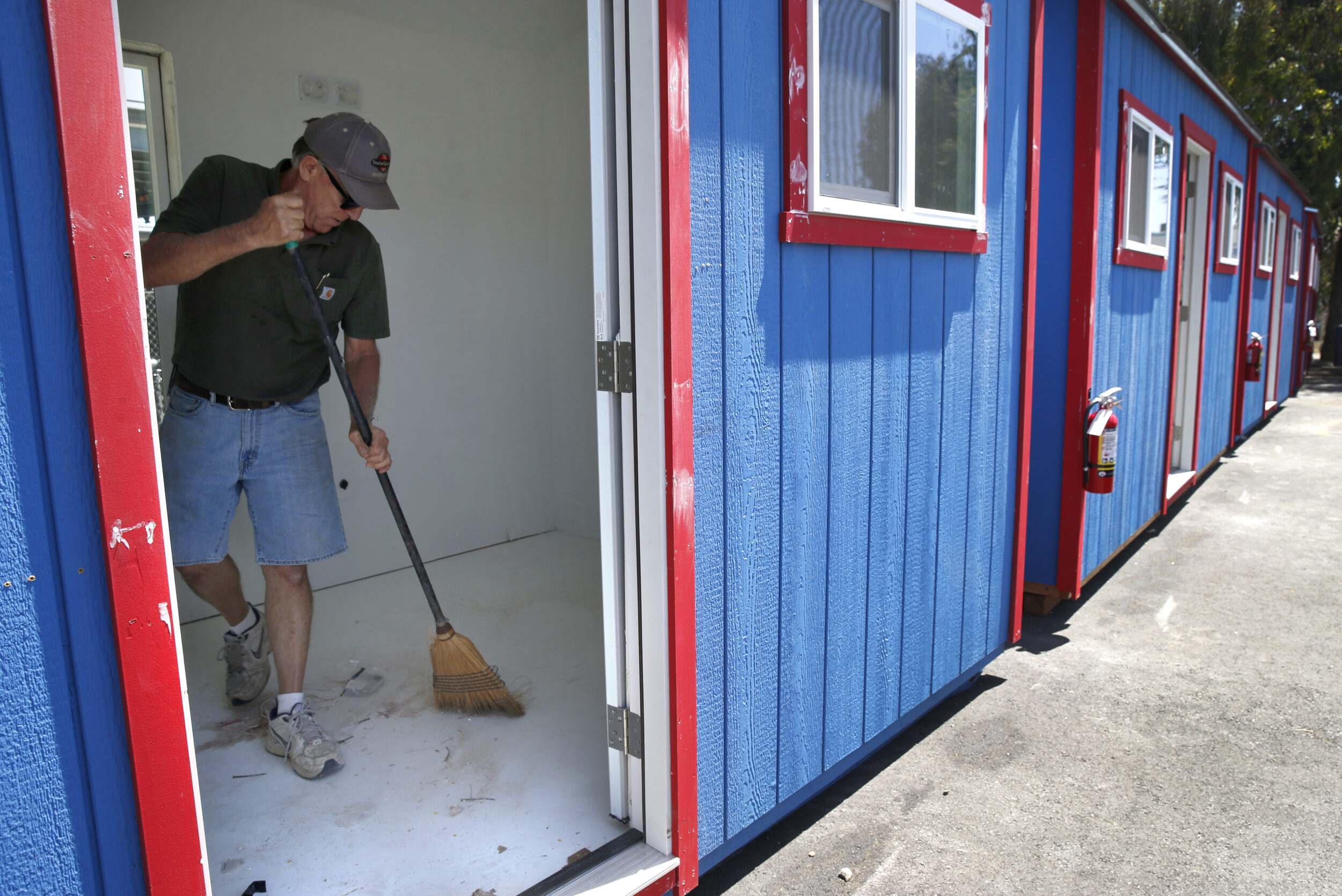A person cleans a shelter's floor with a broom.