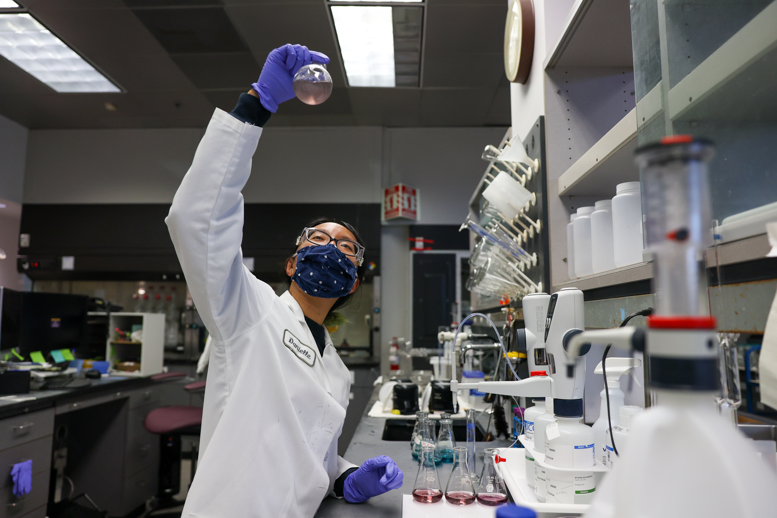 A woman in a lab coat examines a vial.