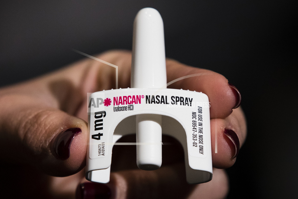 A hand holding a Narcan nasal spray device, used for emergency opioid overdose treatment.