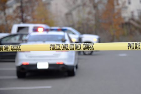 good books you can find at the library Police tape is seen close up, with a police patrol vehicle some distance beyond.