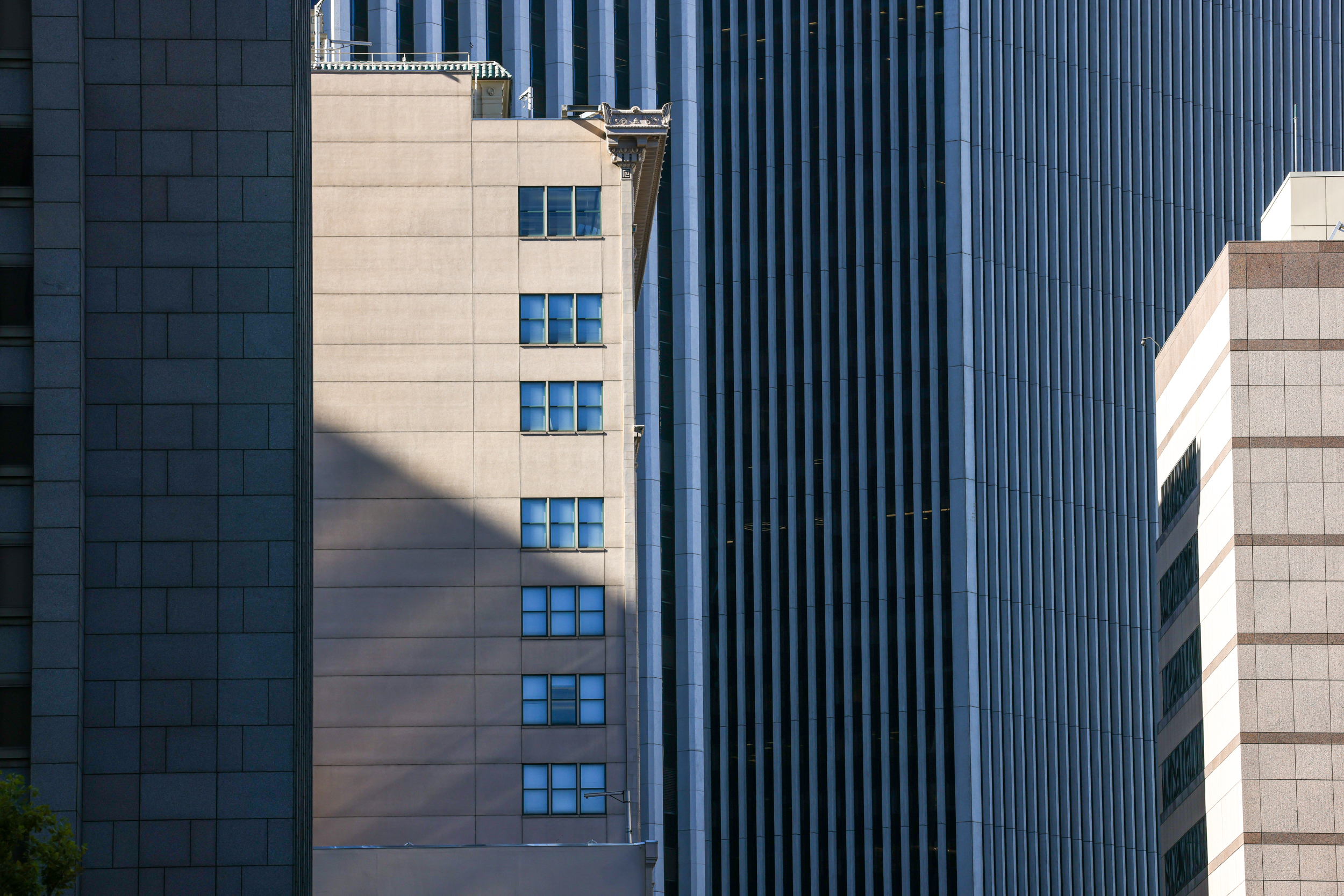 Facade of three different buildings with contrasting designs and a shadow dividing one.