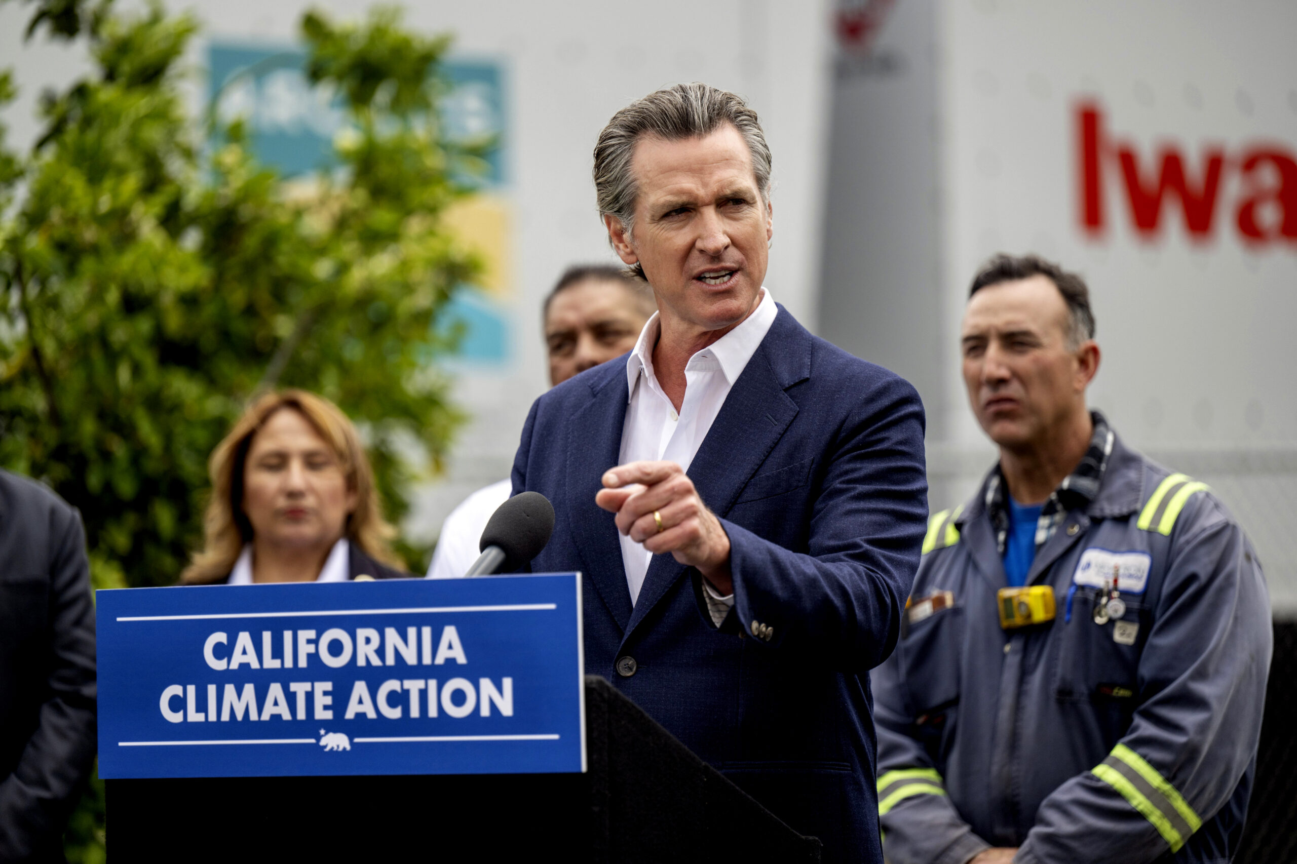 Gov. Gavin Newsom speaks at a press conference behind a podium reading "California Climate Action"