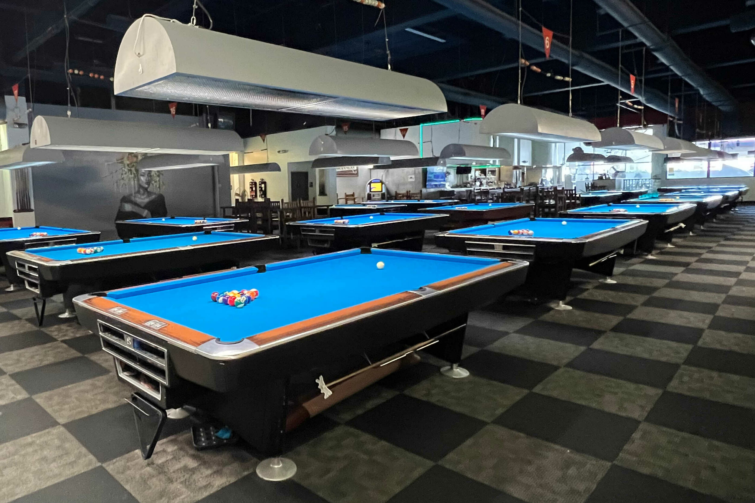 Several billiards tables are lined up in a room.