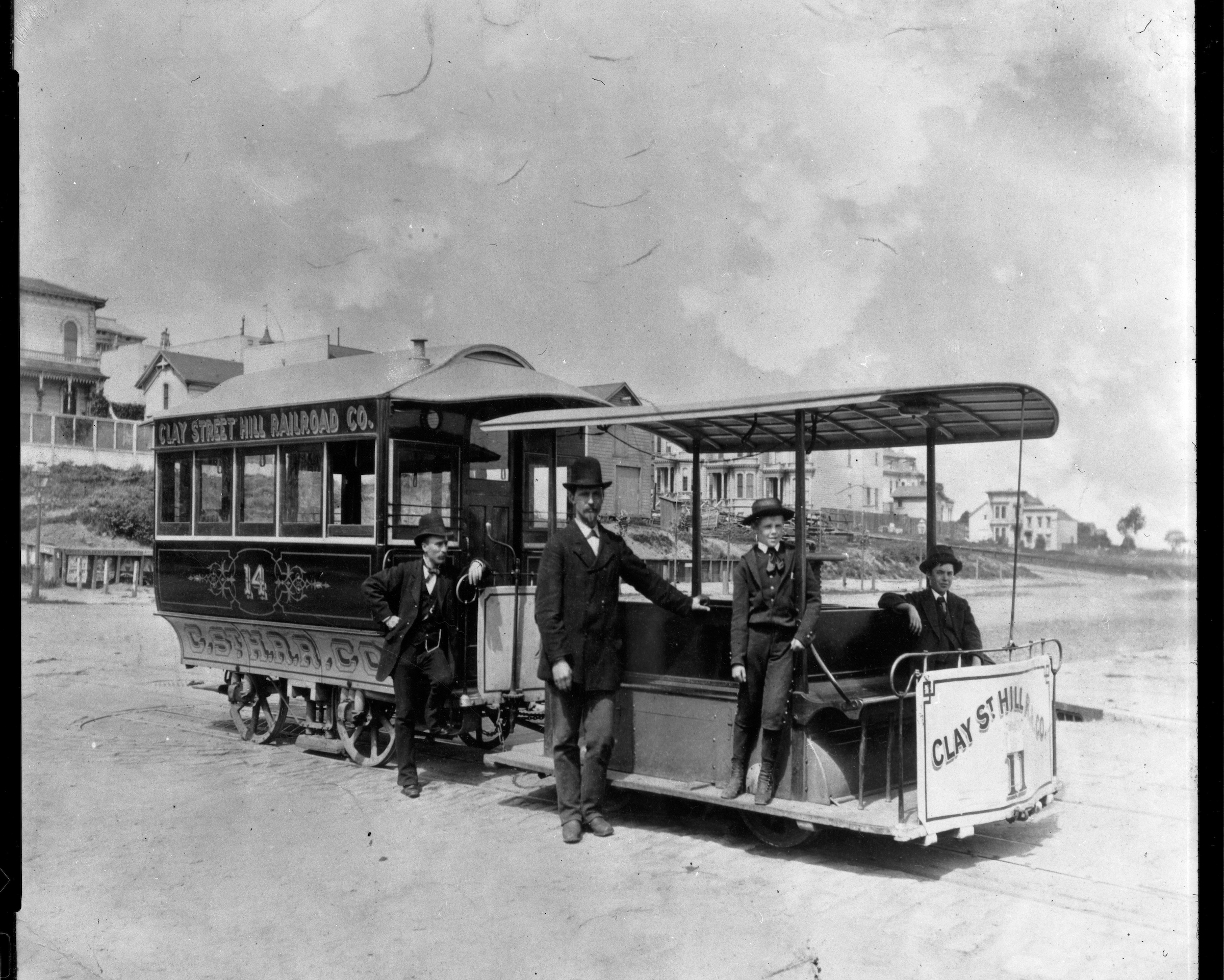 A vintage photo of a San Francisco cable car with a group of men standing before it.