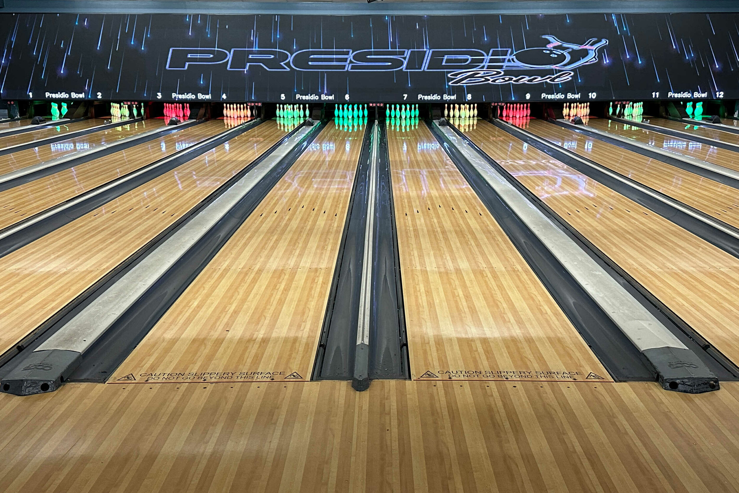 Bowling lanes with colored pins lined up under the words Presidio Bowl.