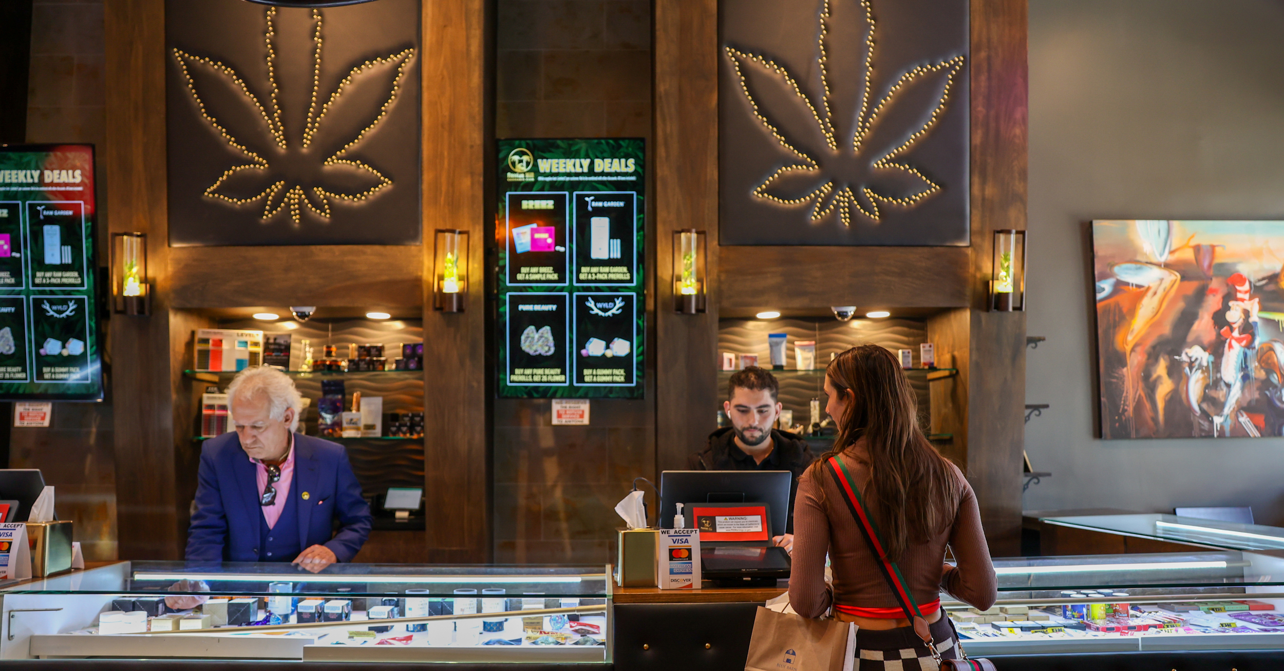 Customers stand at counter at cannabis store