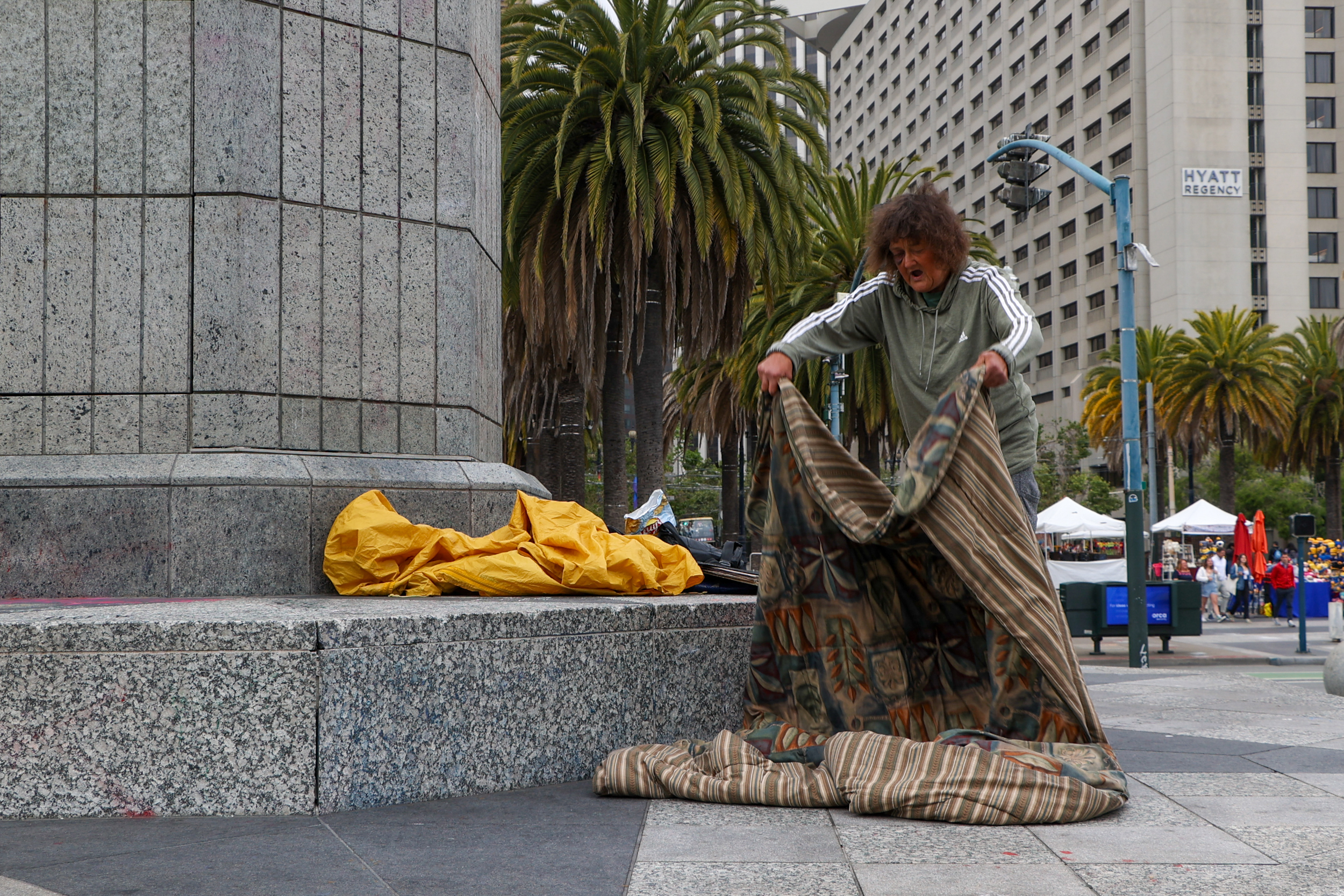 A person prepares a sleeping bag on the street.