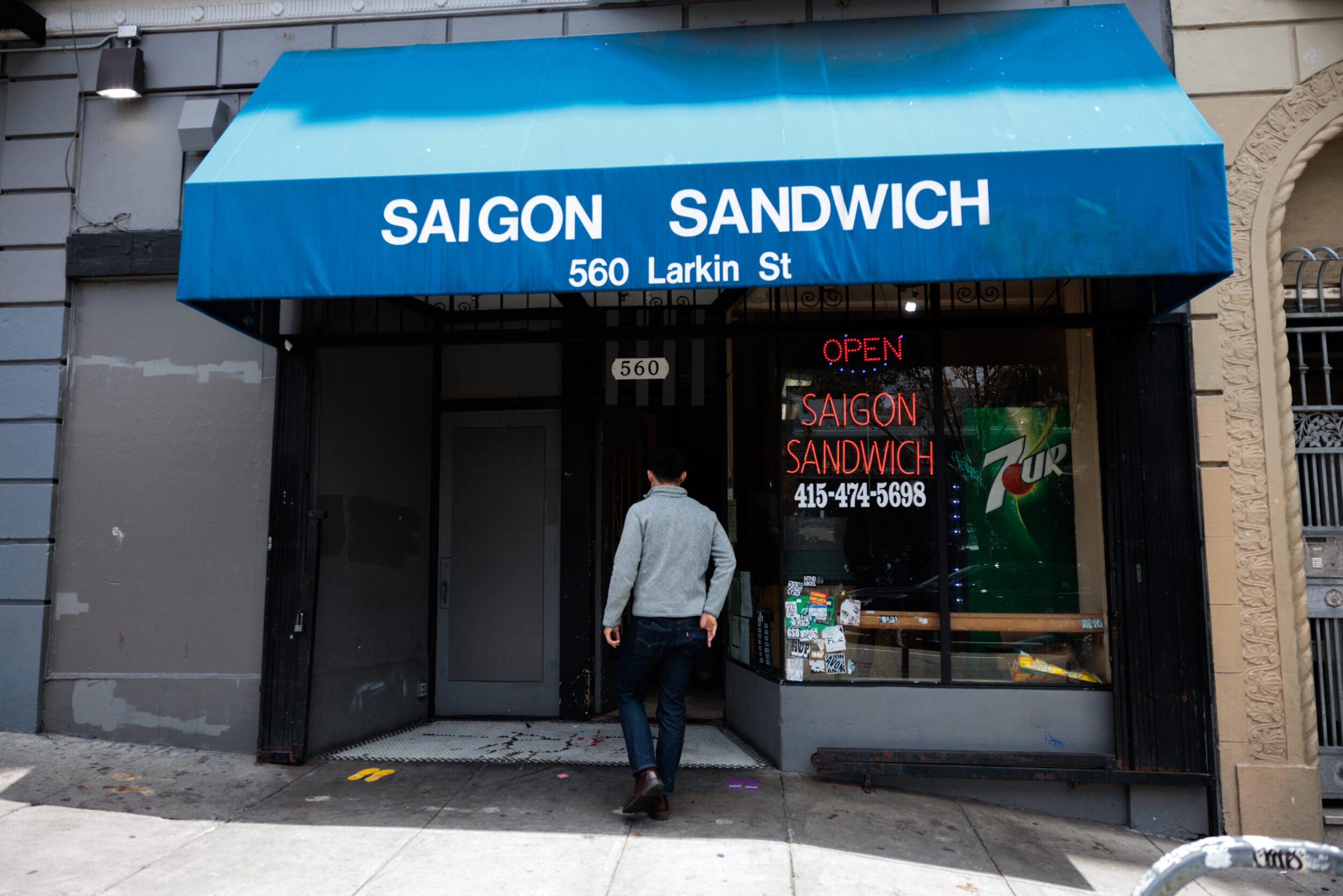 A person enters the storefront of Saigo Sandwich.