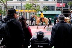A crowd watches a person in a yellow jacket on horseback.