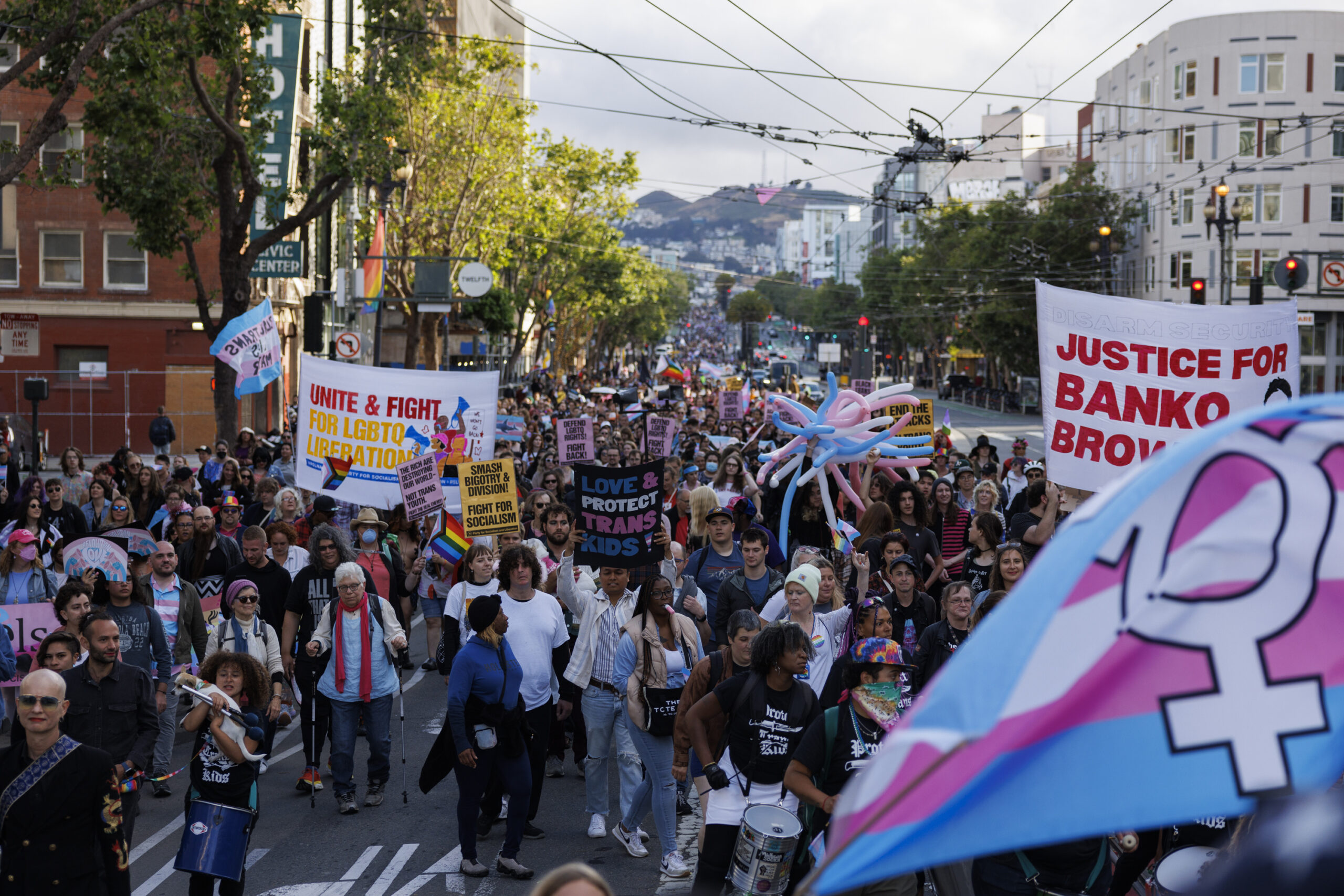 Trans march participants wield banners, flags and balloons as they parade down Market Street, in San Francisco, on June 23, 2023. 