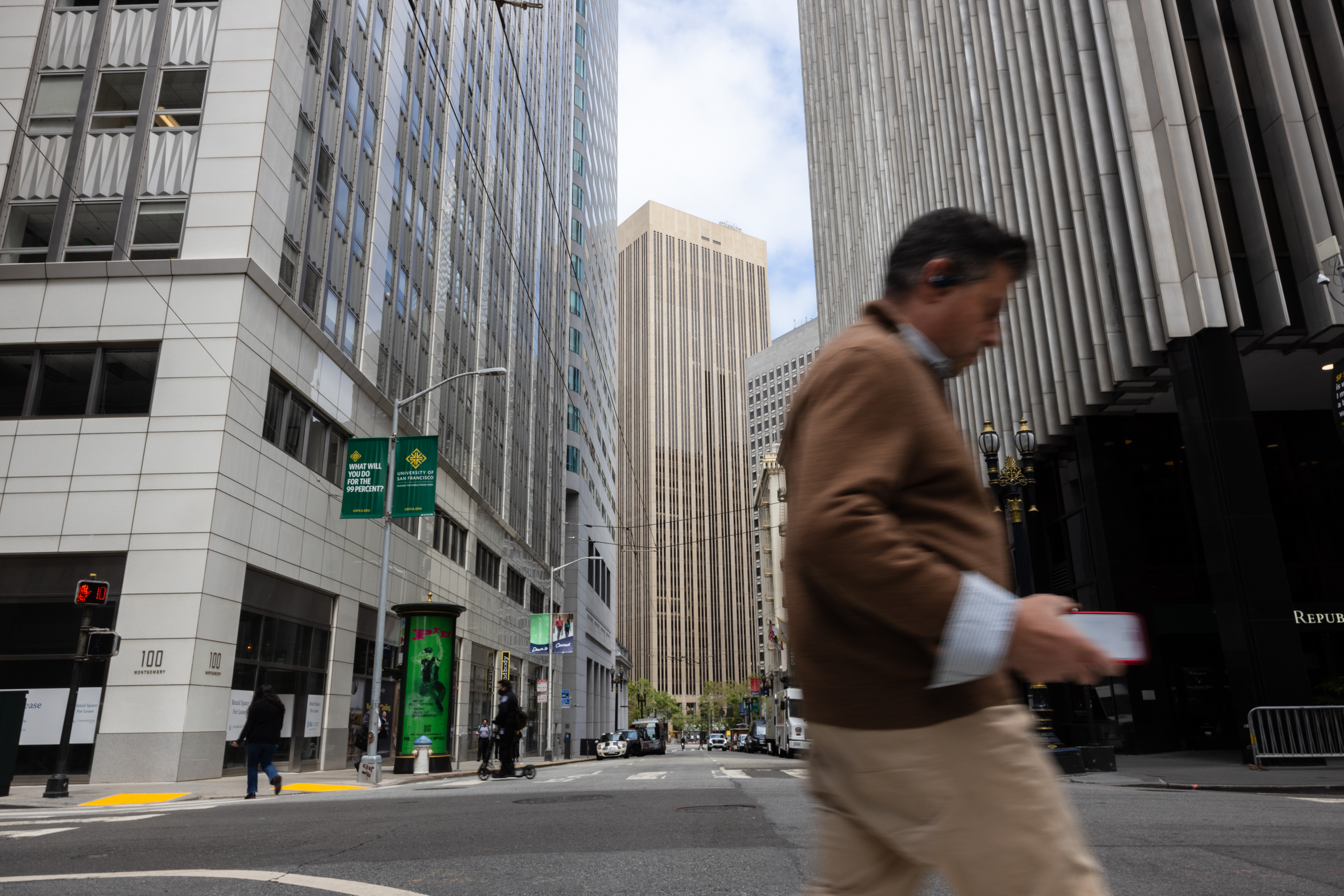 A pedestrian walks across the street on Montgomery Street and Sutter Street in the Financial District in San Francisco.