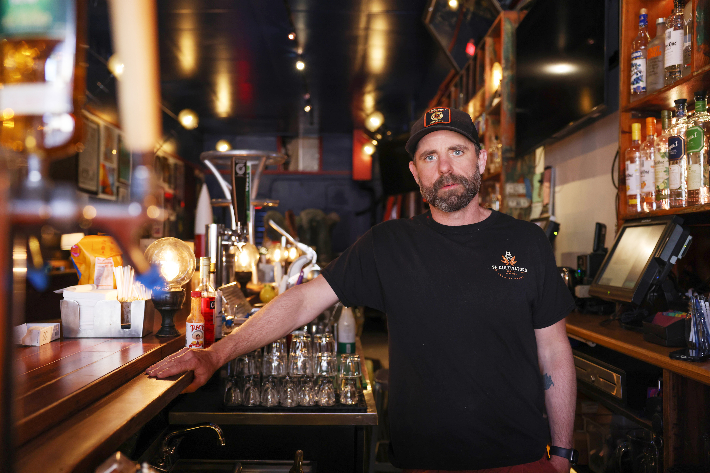 A man wearing black shirt stands at a bar.