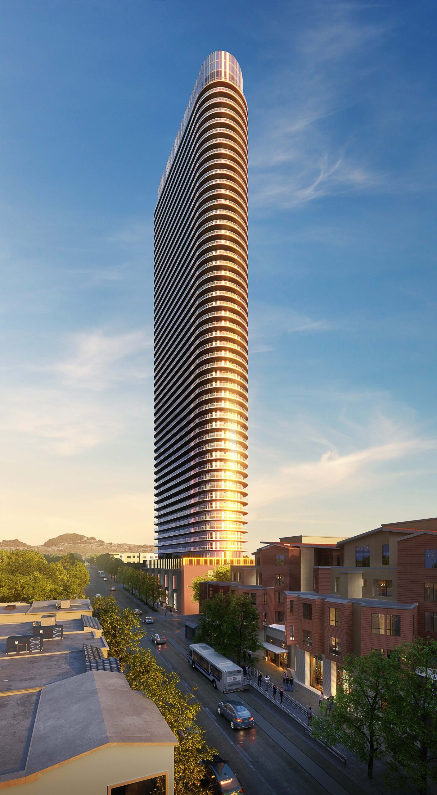 A sleek, modern high-rise with a rounded top towers over a busy street with cars and a bus, surrounded by mid-rise buildings and trees, under a clear sky.