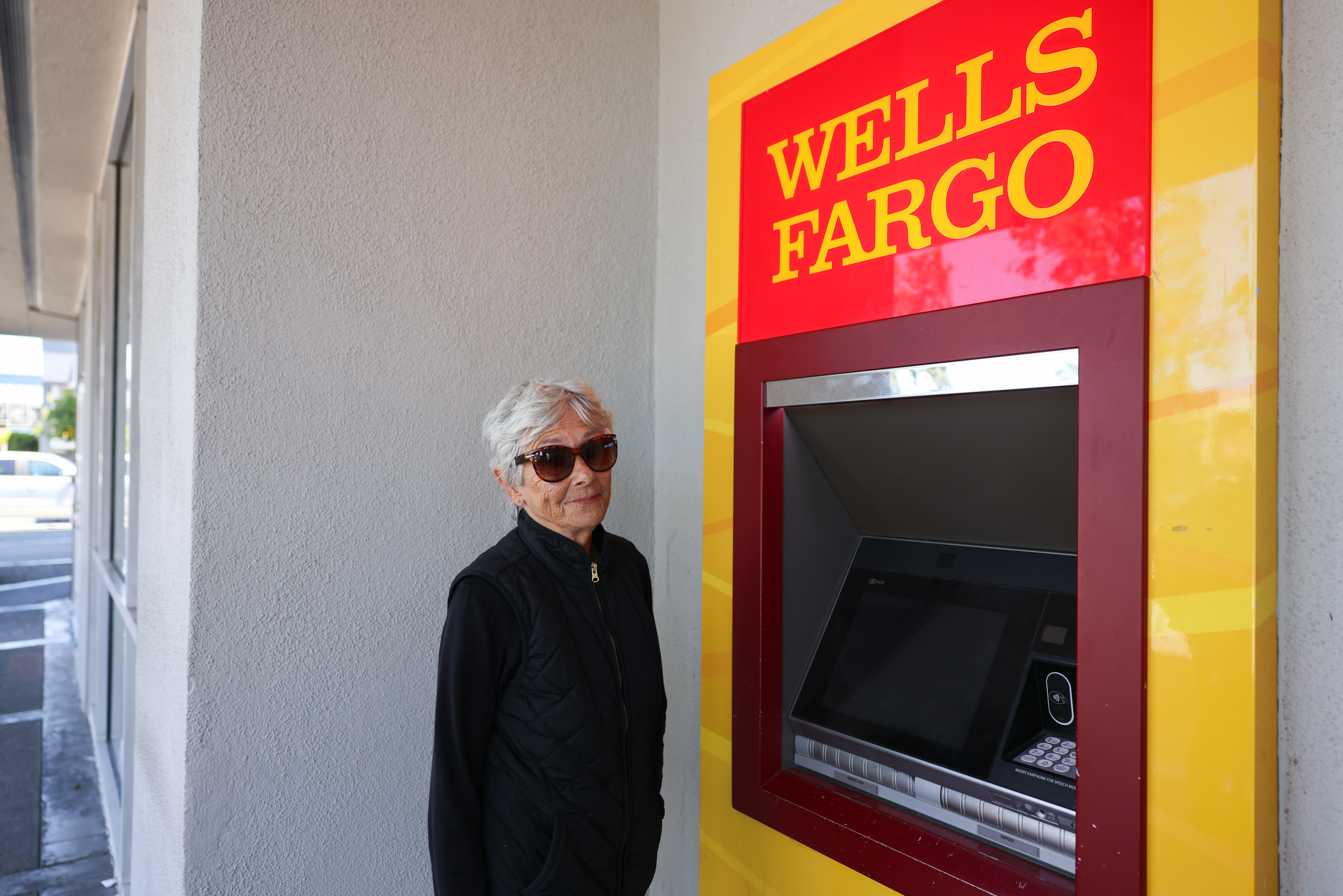 A man stands in front of a Wells Fargo bank in the Bayview neighborhood of San Francisco.