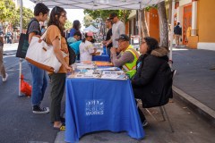 A street booth with &quot;San Francisco Public Works&quot; banner and people discussing pamphlets.