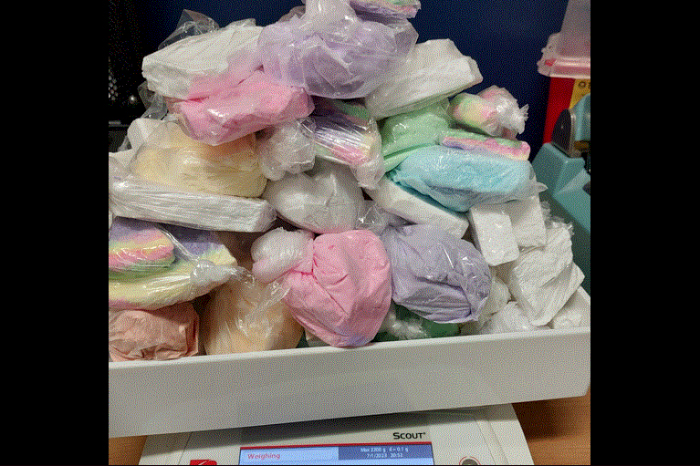 A pile of colorful, plastic-wrapped drugs on a digital scale.