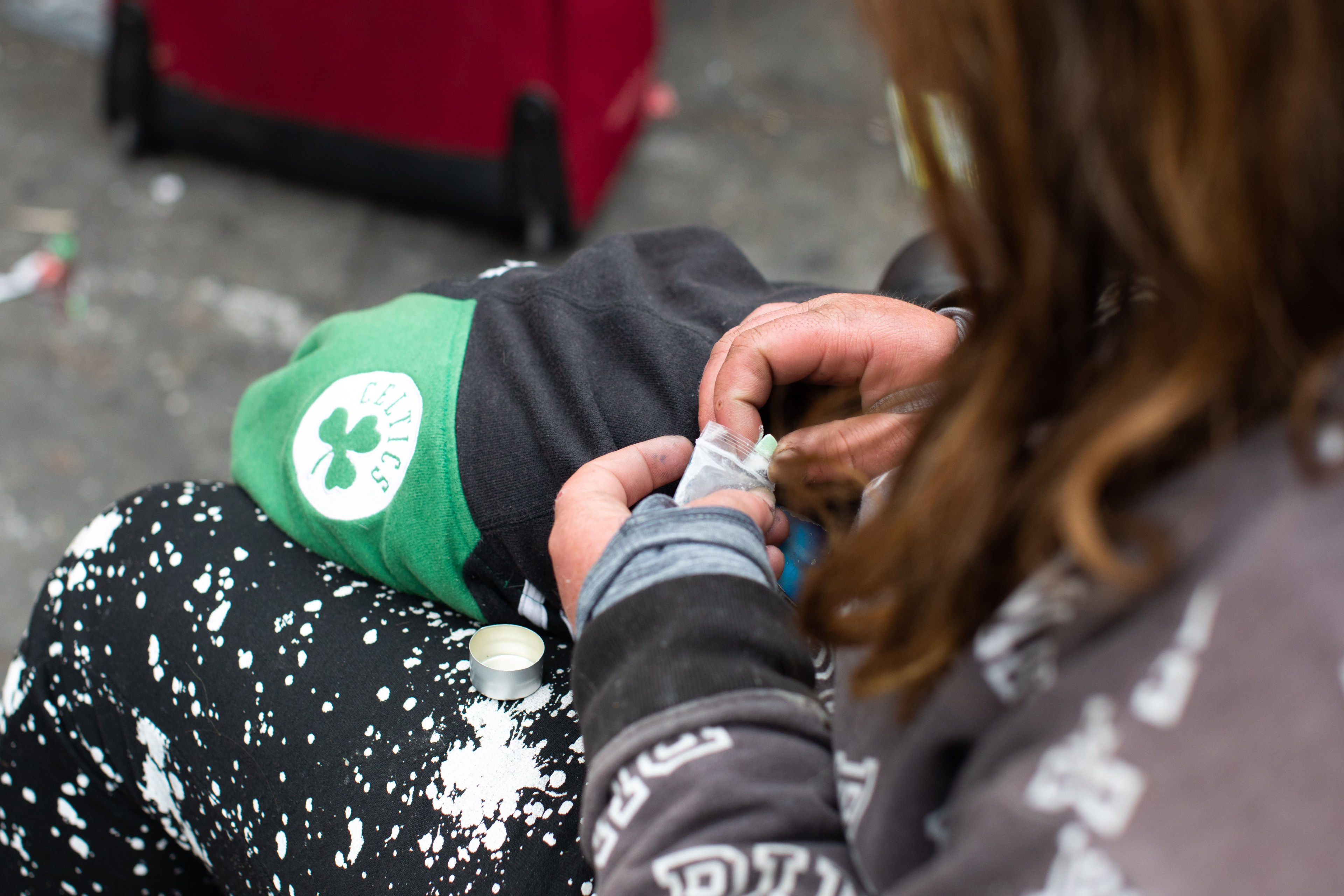 A woman removes drugs from a baggie on the street.