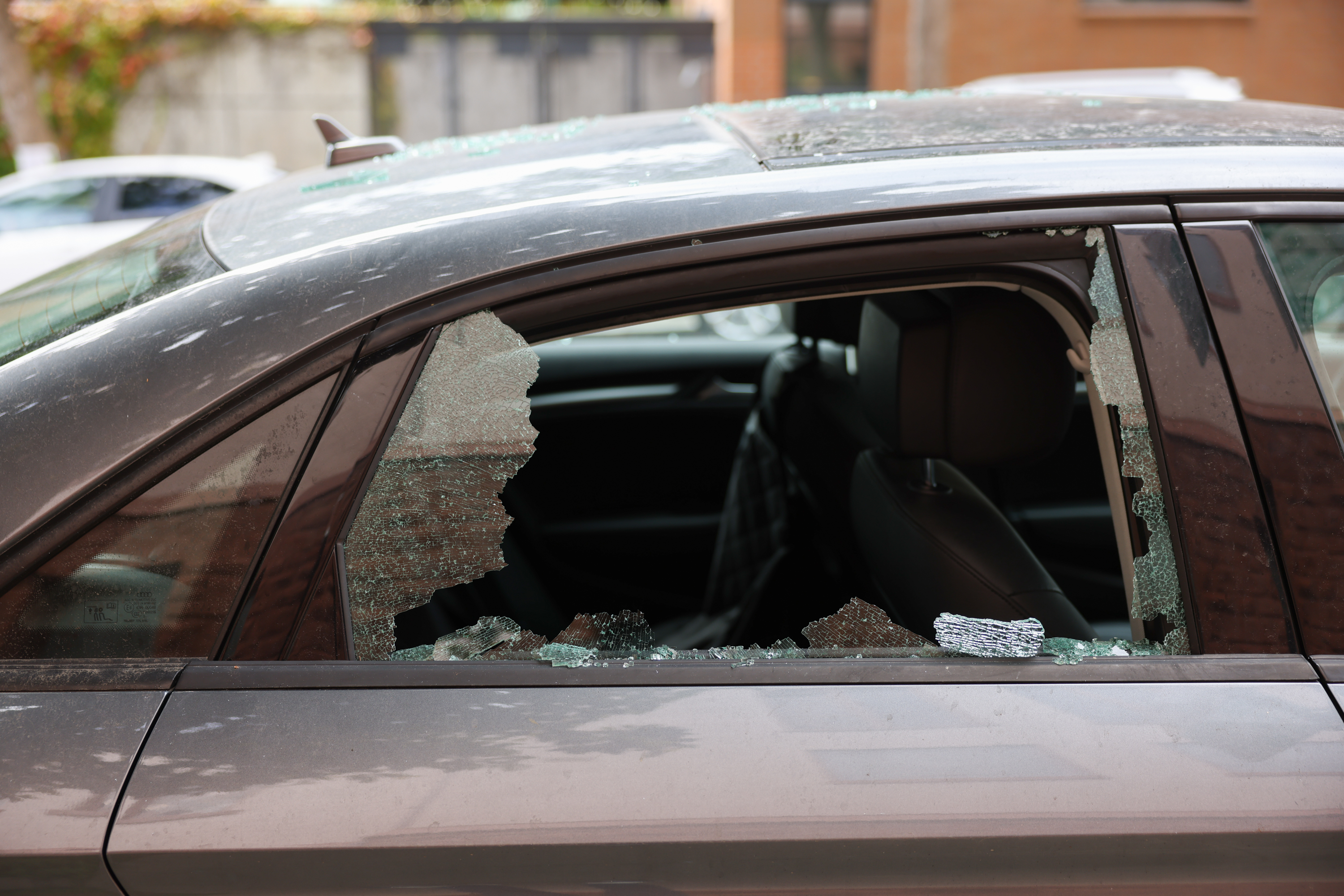Broken glass sits in the window of a car