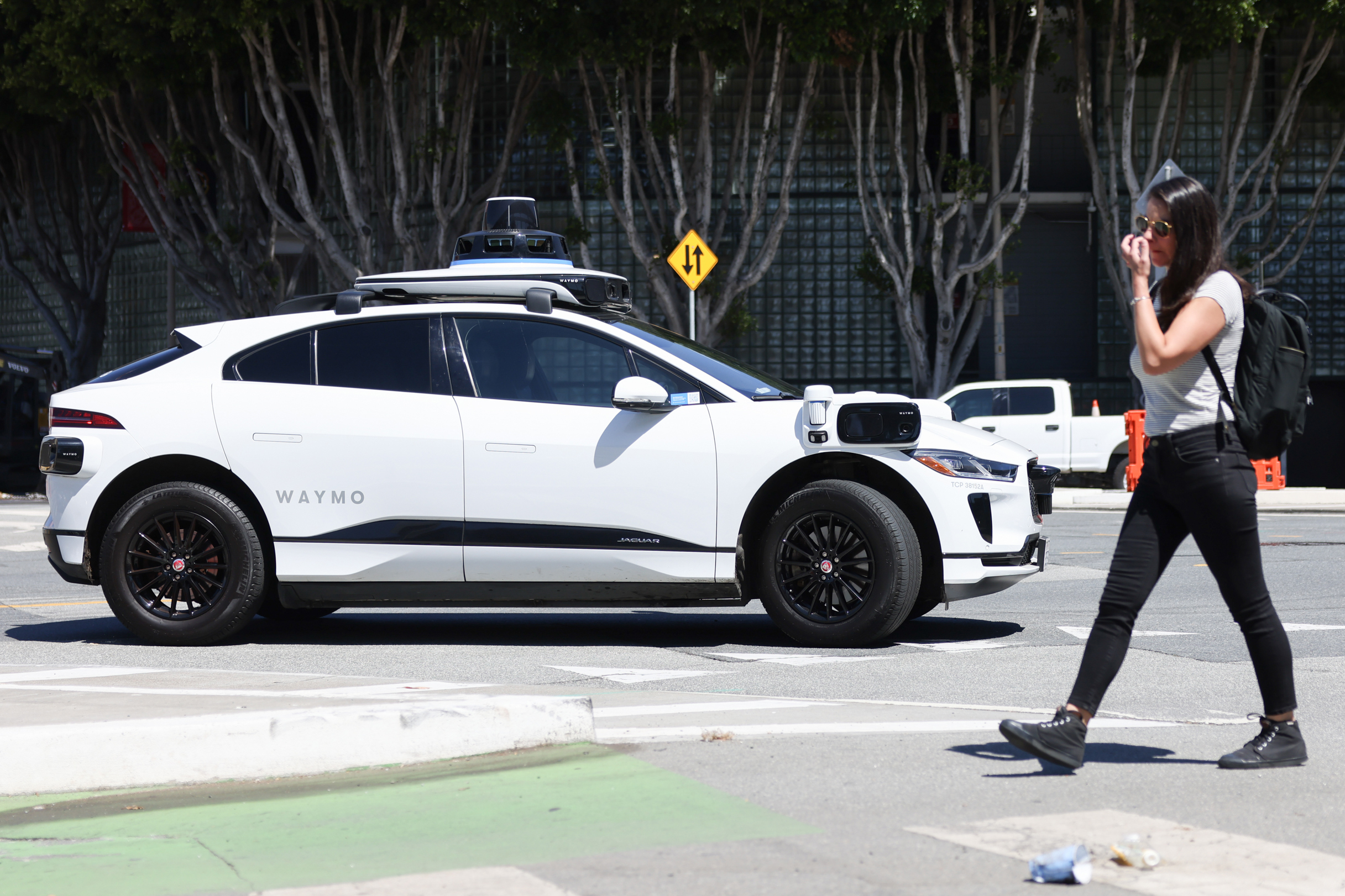 A Waymo self-driving car and a pedestrian crossing the street.