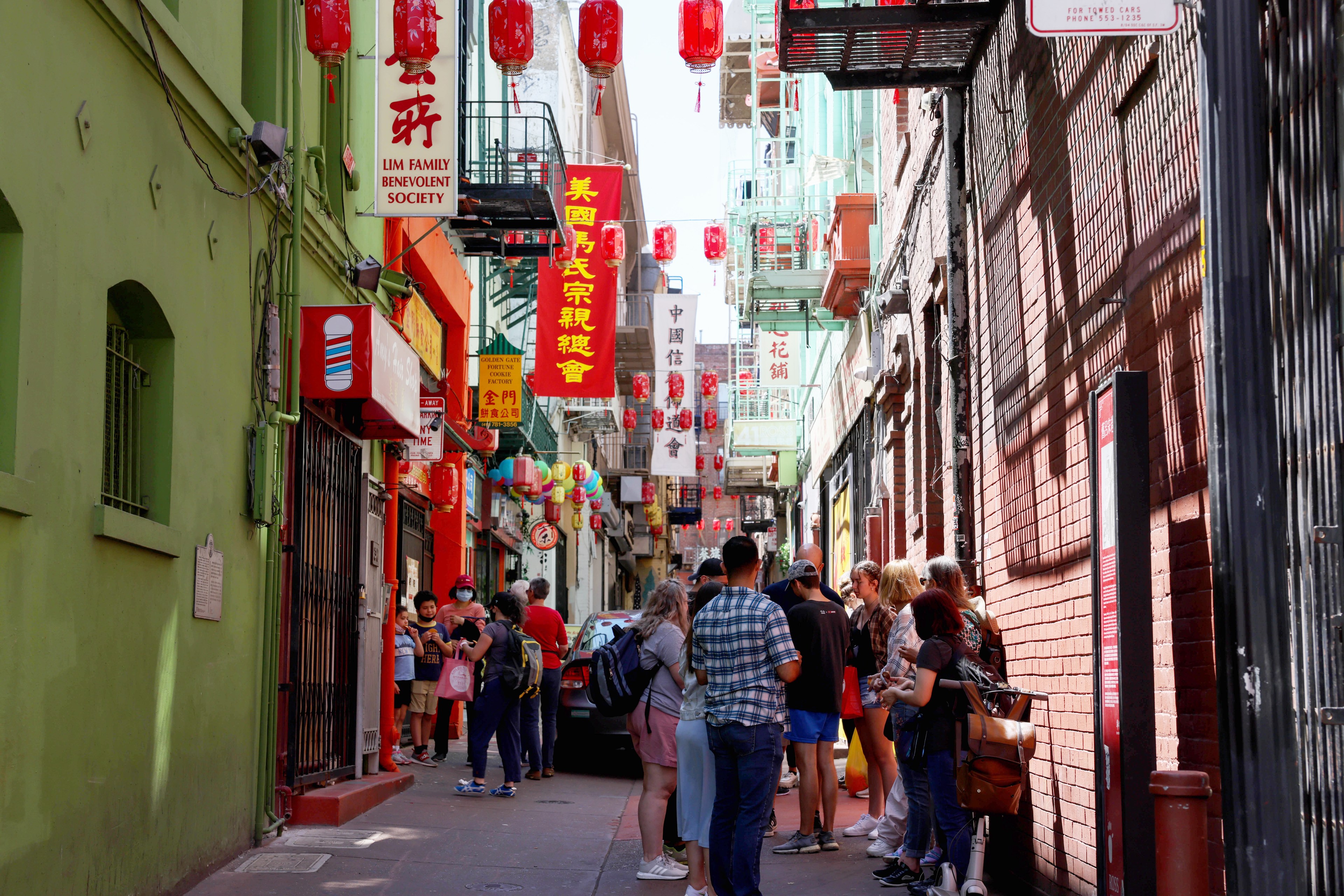 People walk on Ross Alley in Chinatown, San Francisco on Wednesday, June 22nd, 2022. The alley is full of restaurants and shops and is a popular location for tourists.