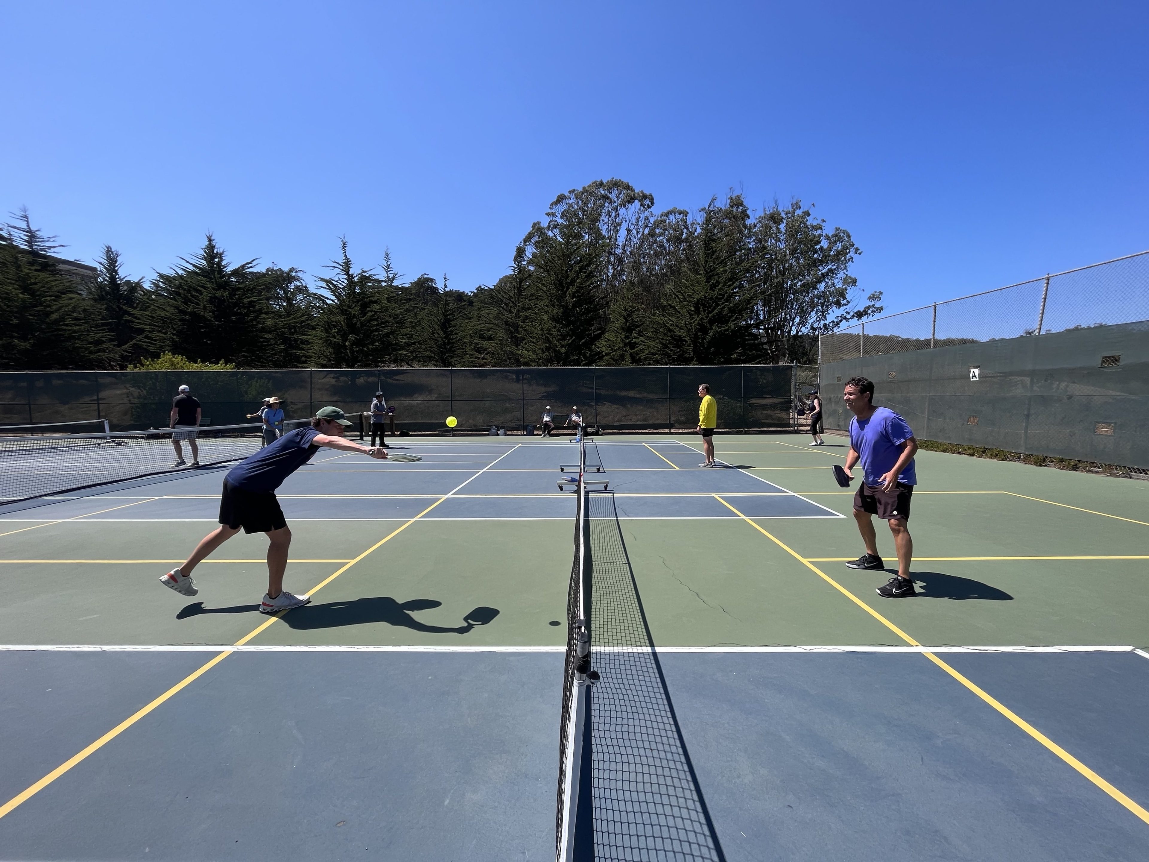 Two men face off in a match of pickleball on a sunny day in San Francisco.