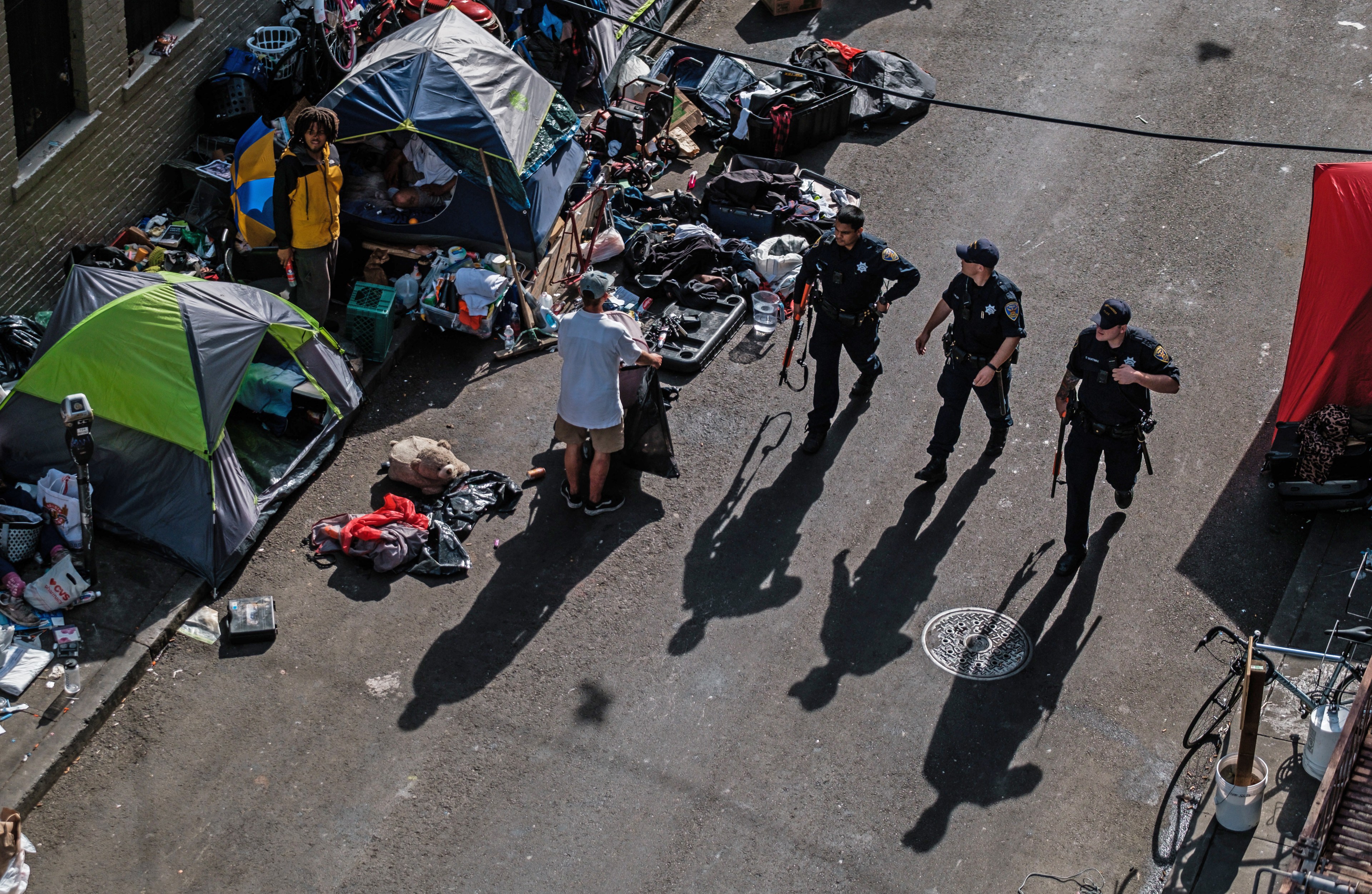 Police officers are seen from above walking past tents.