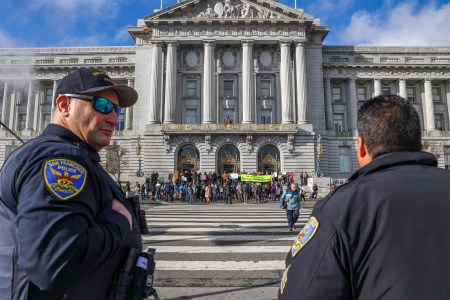 Police officers observe a protest in front of city hall.