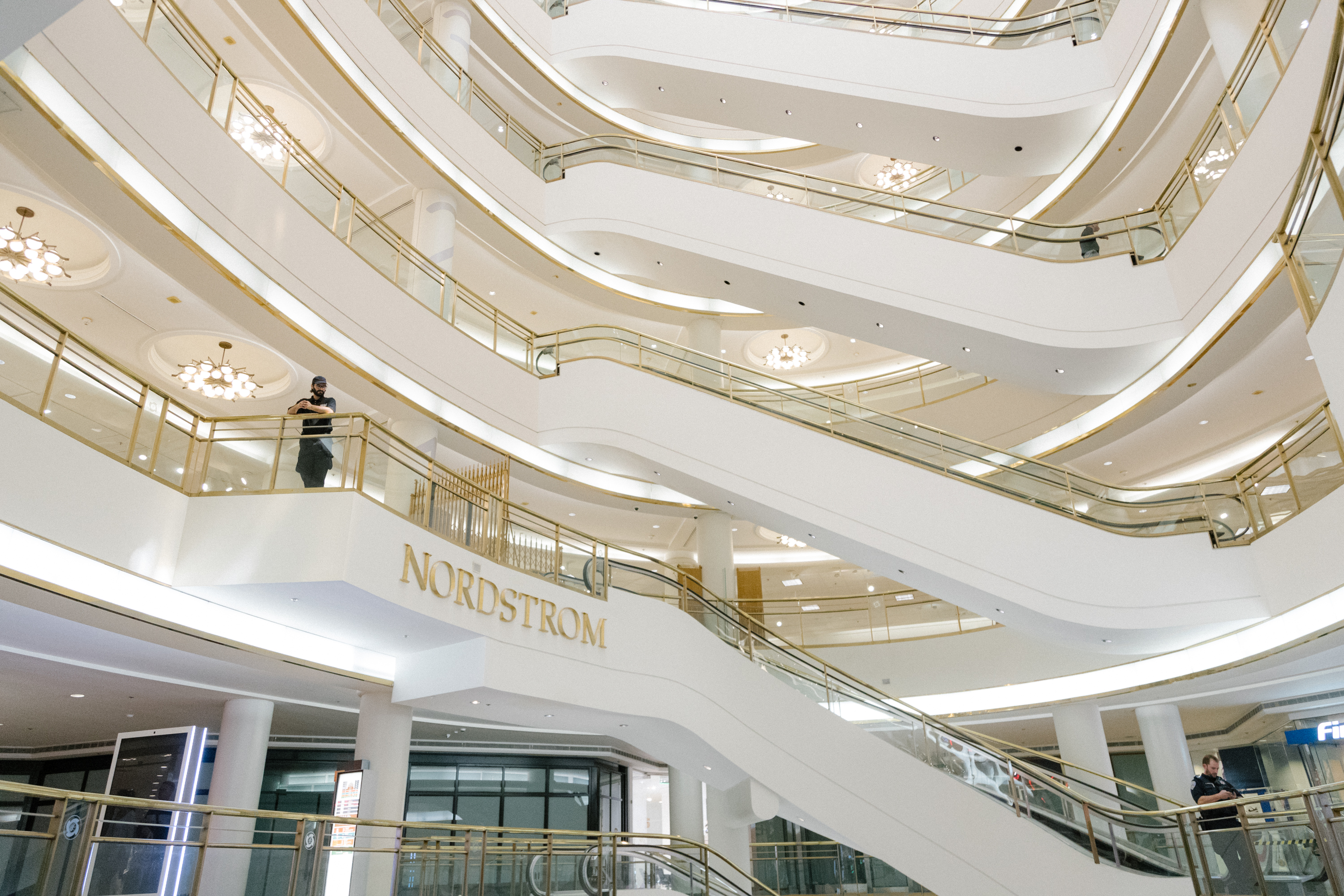 An indoor view of a multi-level shopping area with escalators, elegant railings, and the Nordstrom sign.