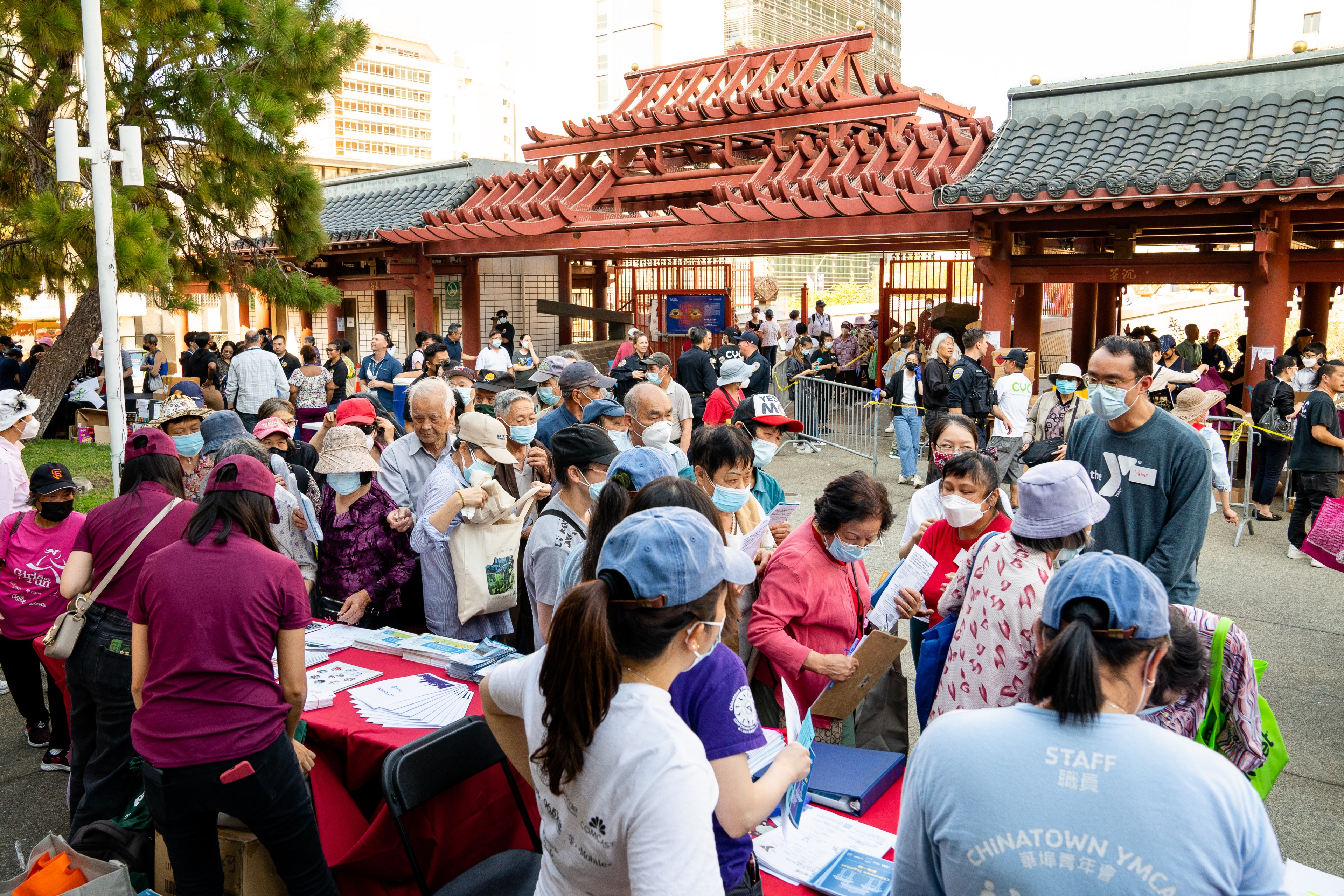 A group of people collects free bags of merchandise from tables in Portsmouth Square in San Francisco's Chinatown. 